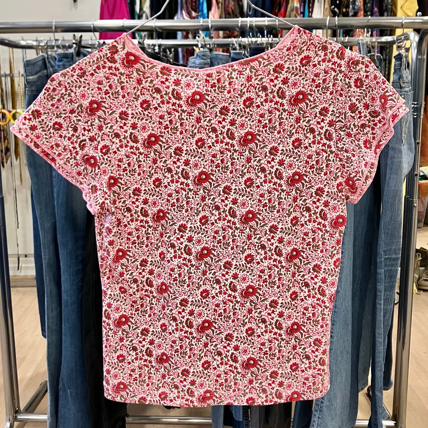 Red floral-patterned shirt on a rack with jeans