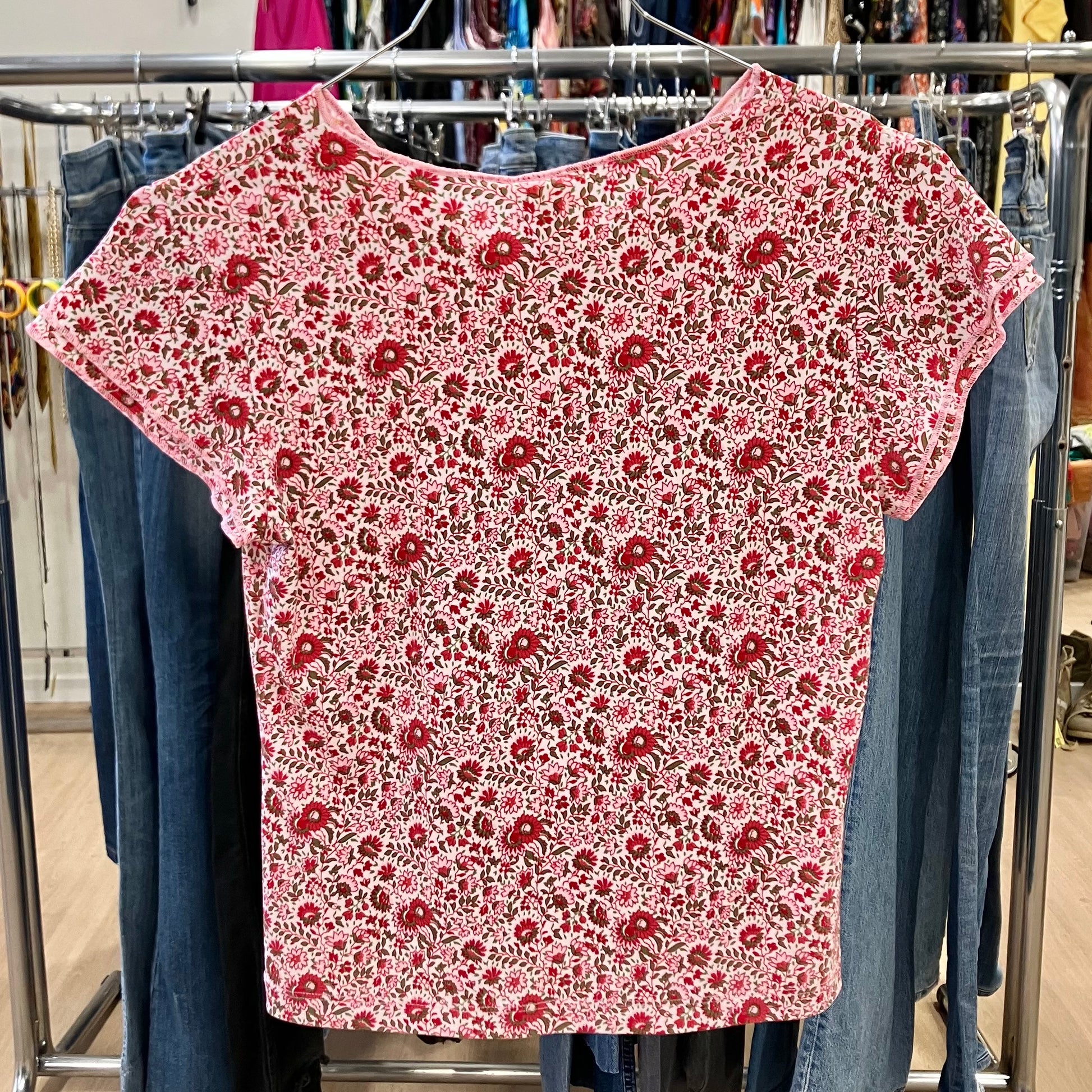 Red floral-patterned shirt on a rack with jeans