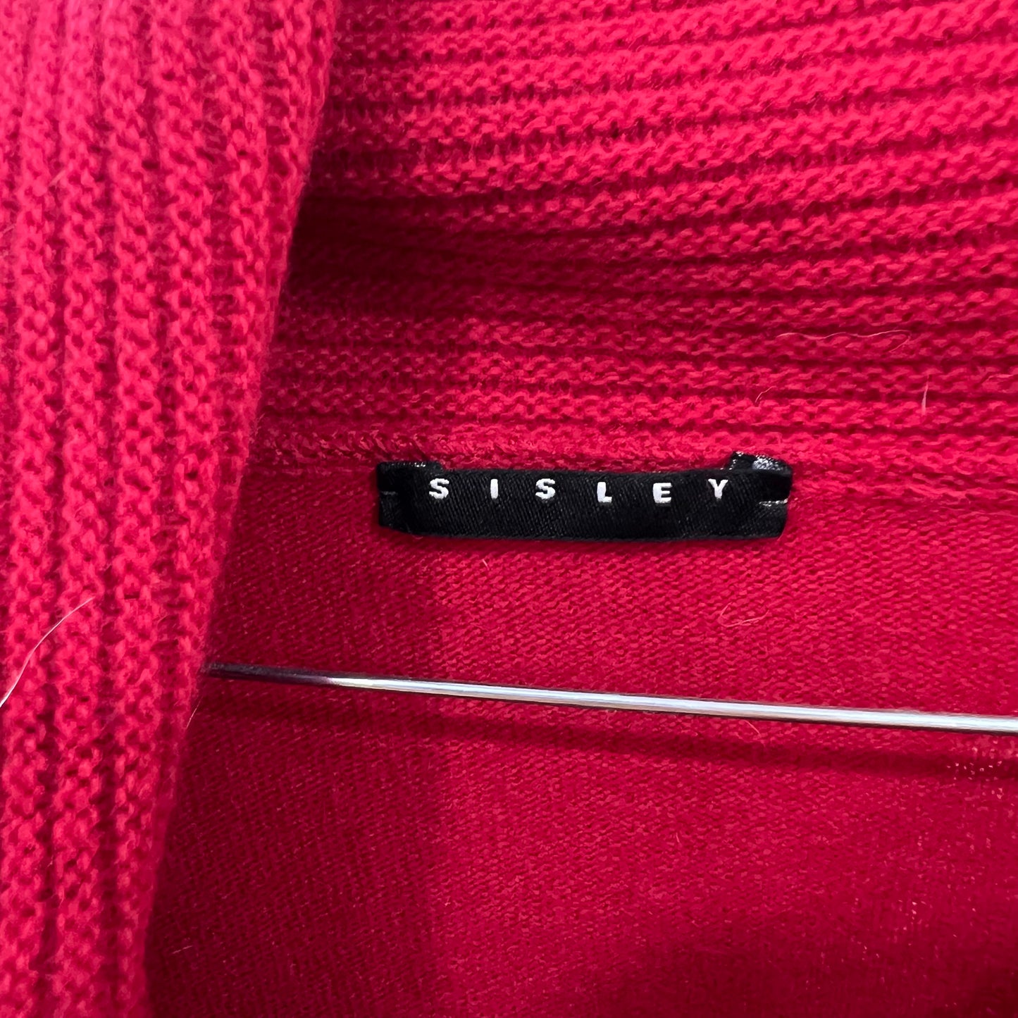 Close-up of a red fabric with a Sisley label.