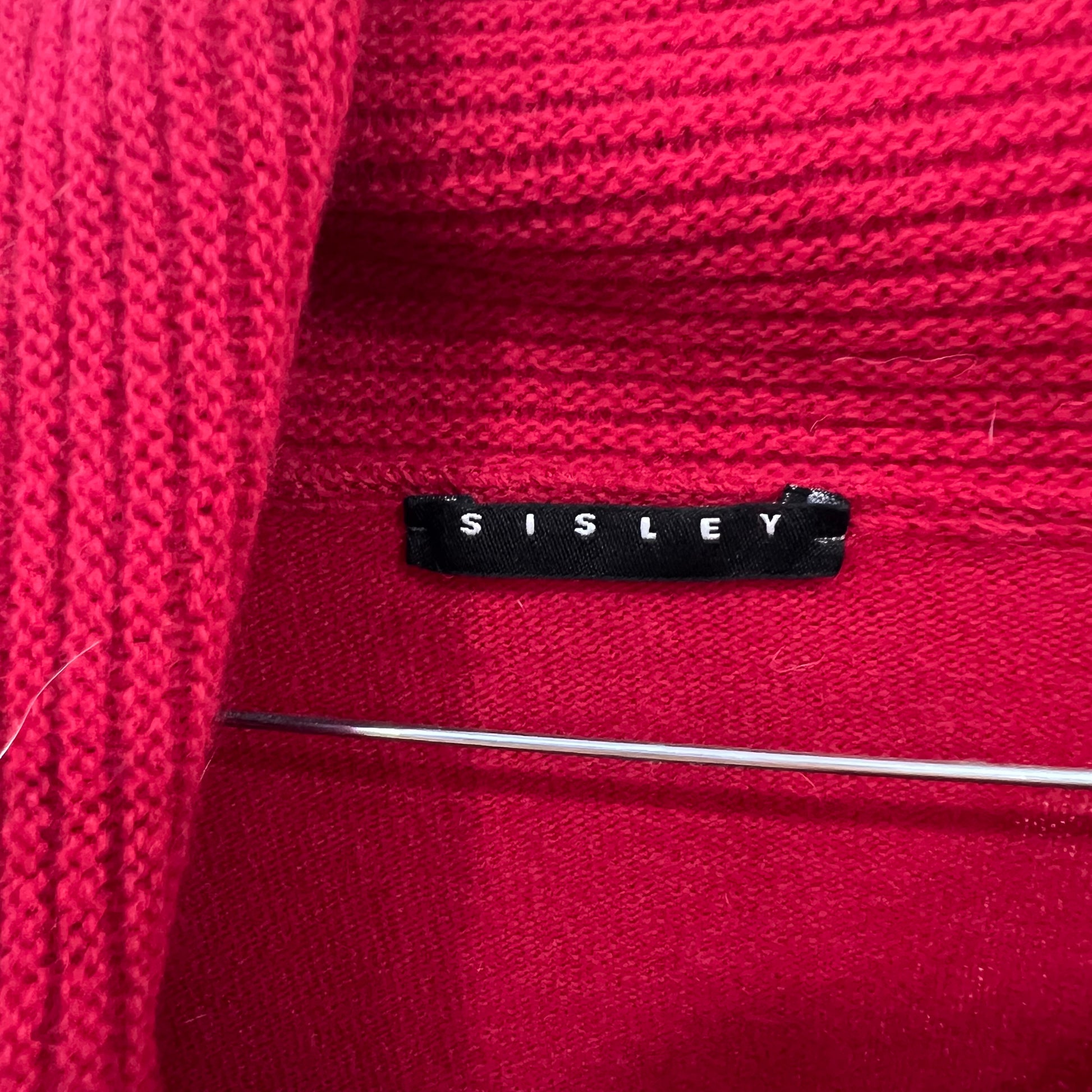 Close-up of a red fabric with a Sisley label.