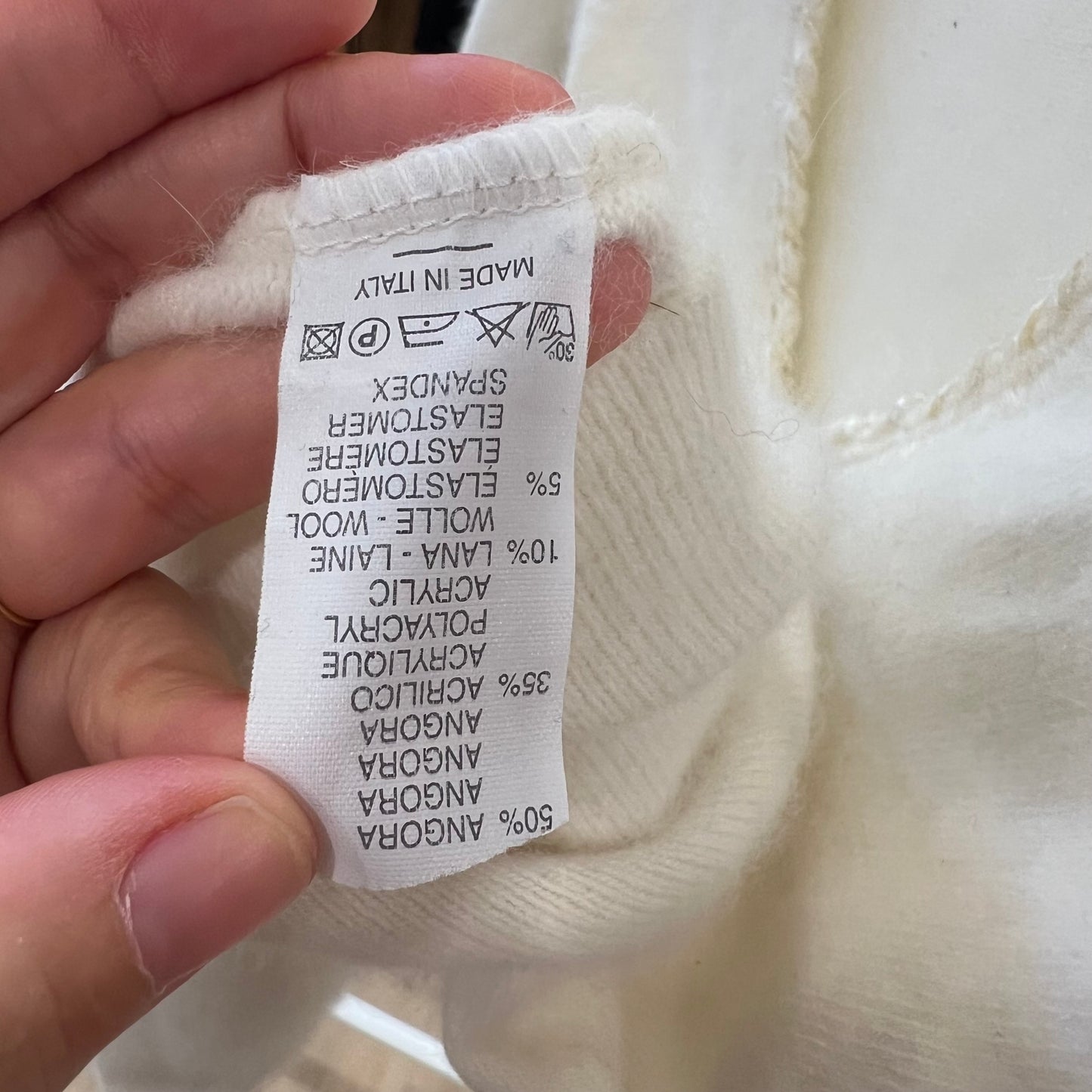 Close-up of a fabric label on white fabric with a hand holding it
