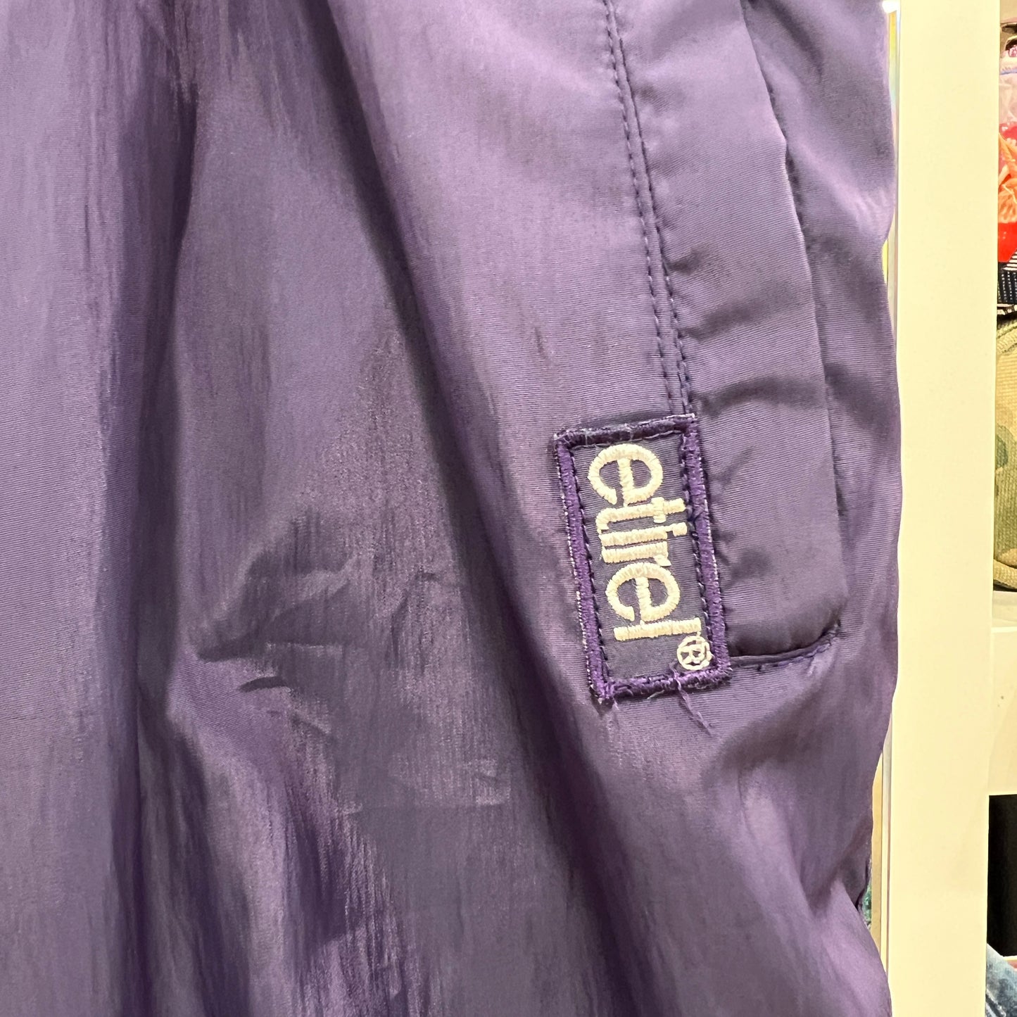 Purple jacket with 'etirel' brand logo on a yellow background