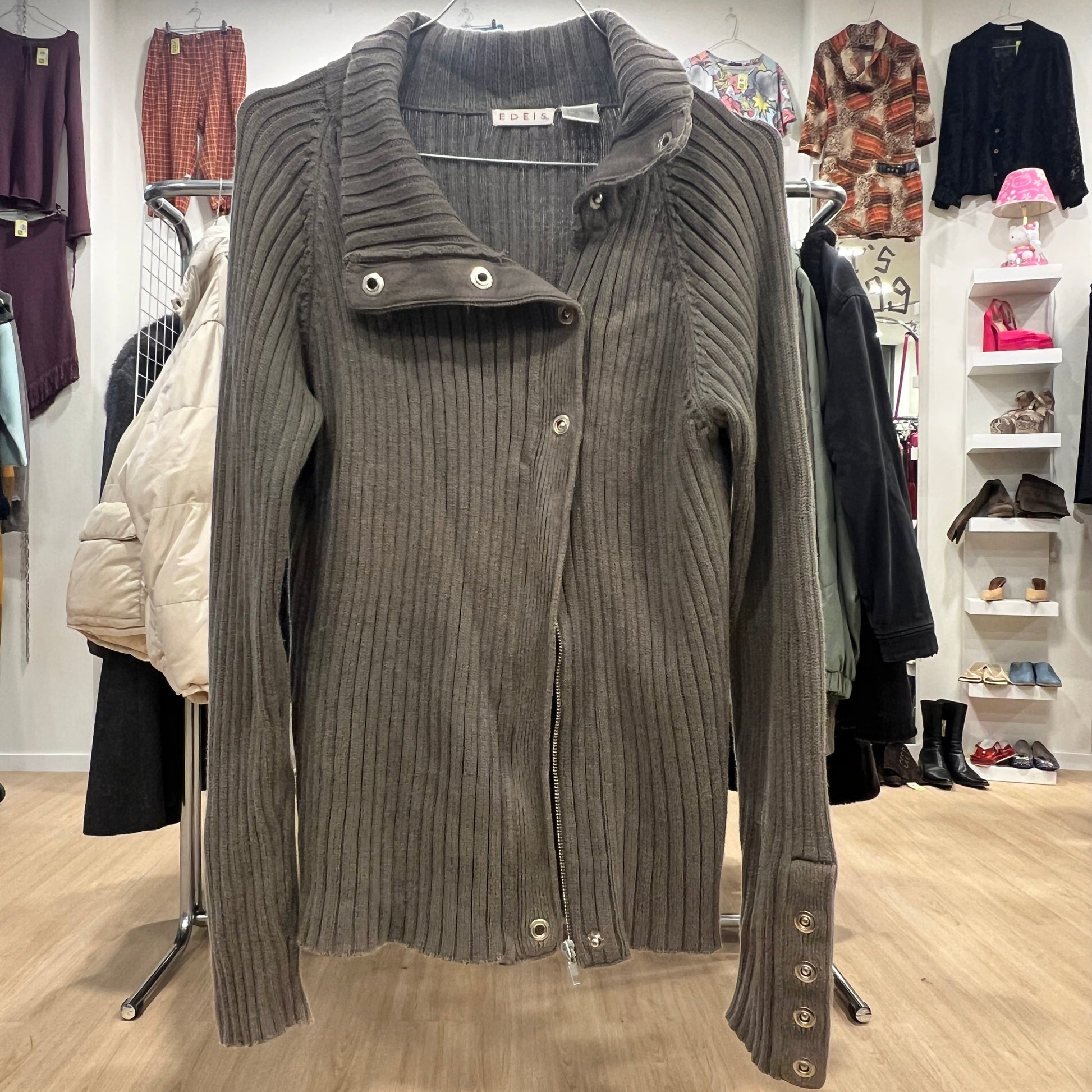 Green ribbed sweater on a hanger with a clothing store background