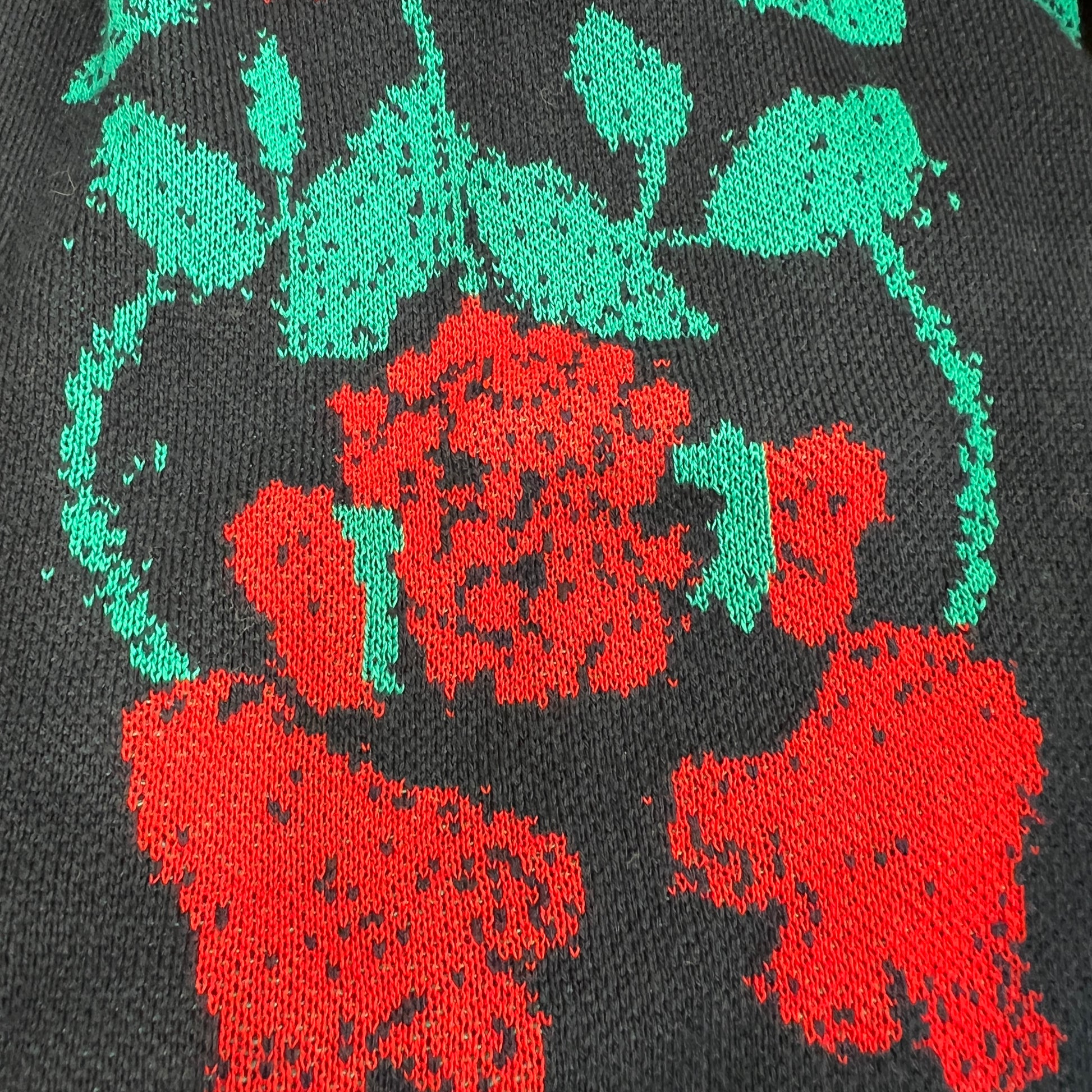 Close-up of a black fabric with red and green floral patterns