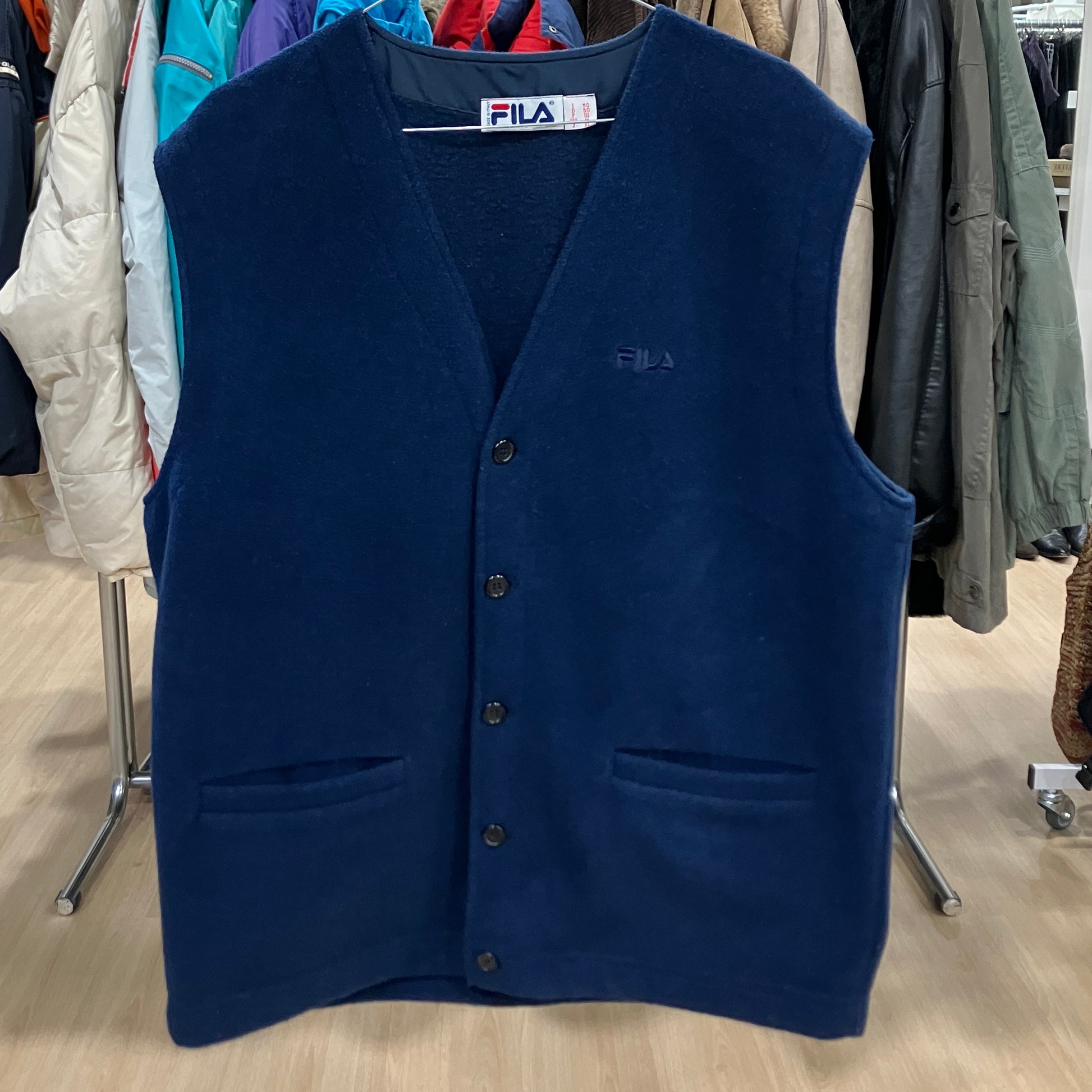Navy blue vest on a hanger with a clothing store background