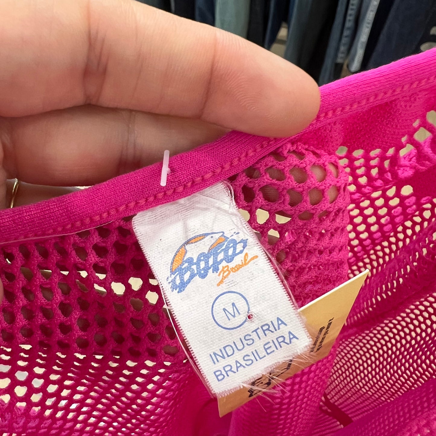 Pink mesh bag with a brand label on a blurred background