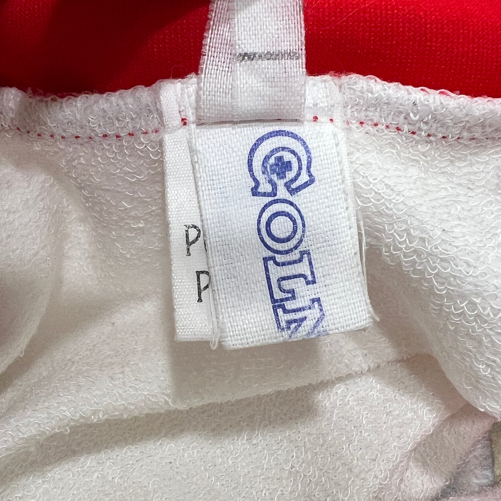 Close-up of a white tag with blue text on a textured white surface