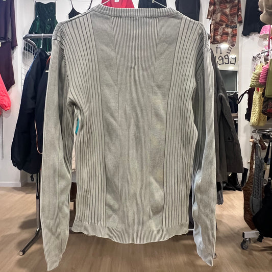Gray ribbed sweater on a hanger in a store setting