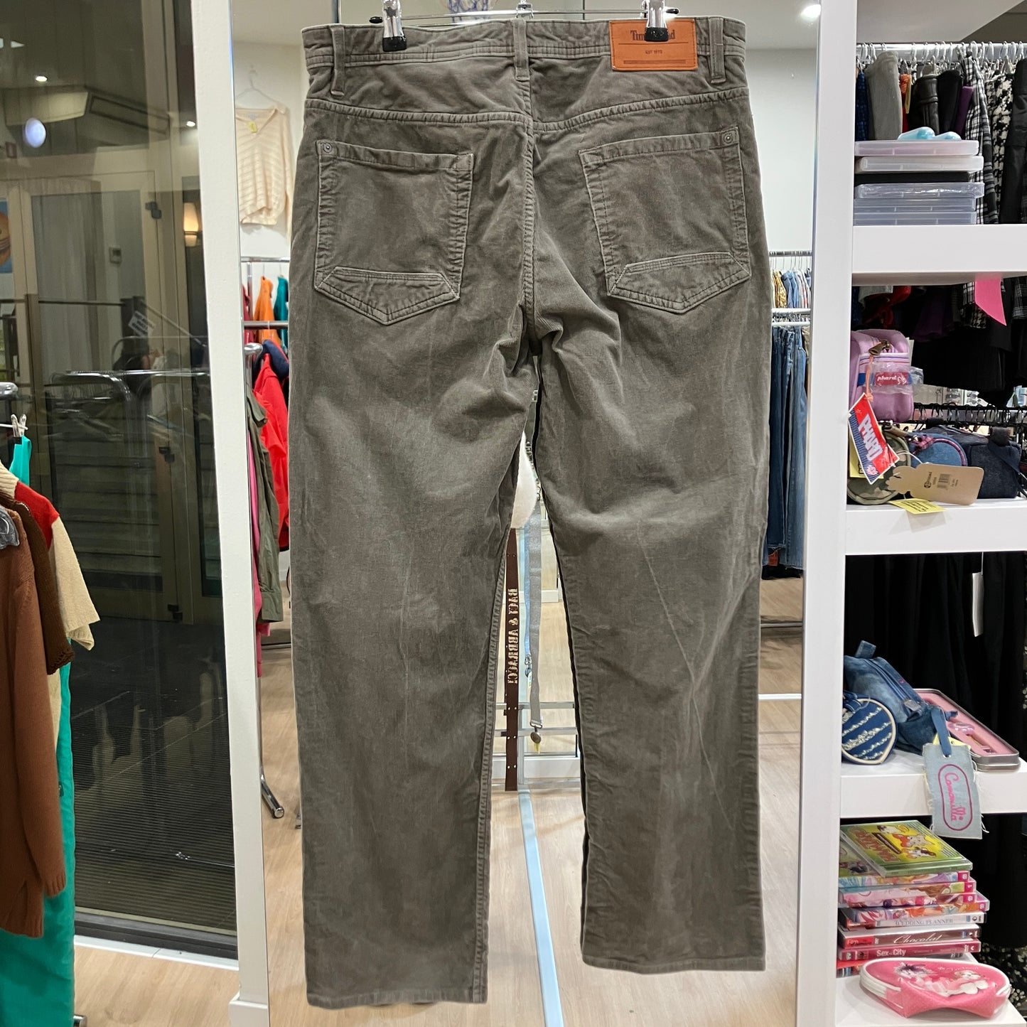 Green pants hanging on a rack in a store setting