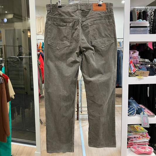 Green pants hanging on a rack in a store setting