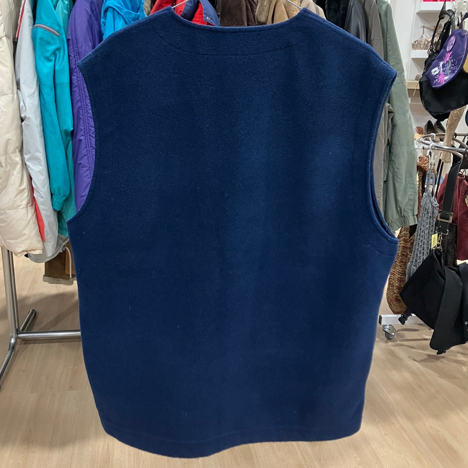 Navy blue vest on a hanger with a clothing store background