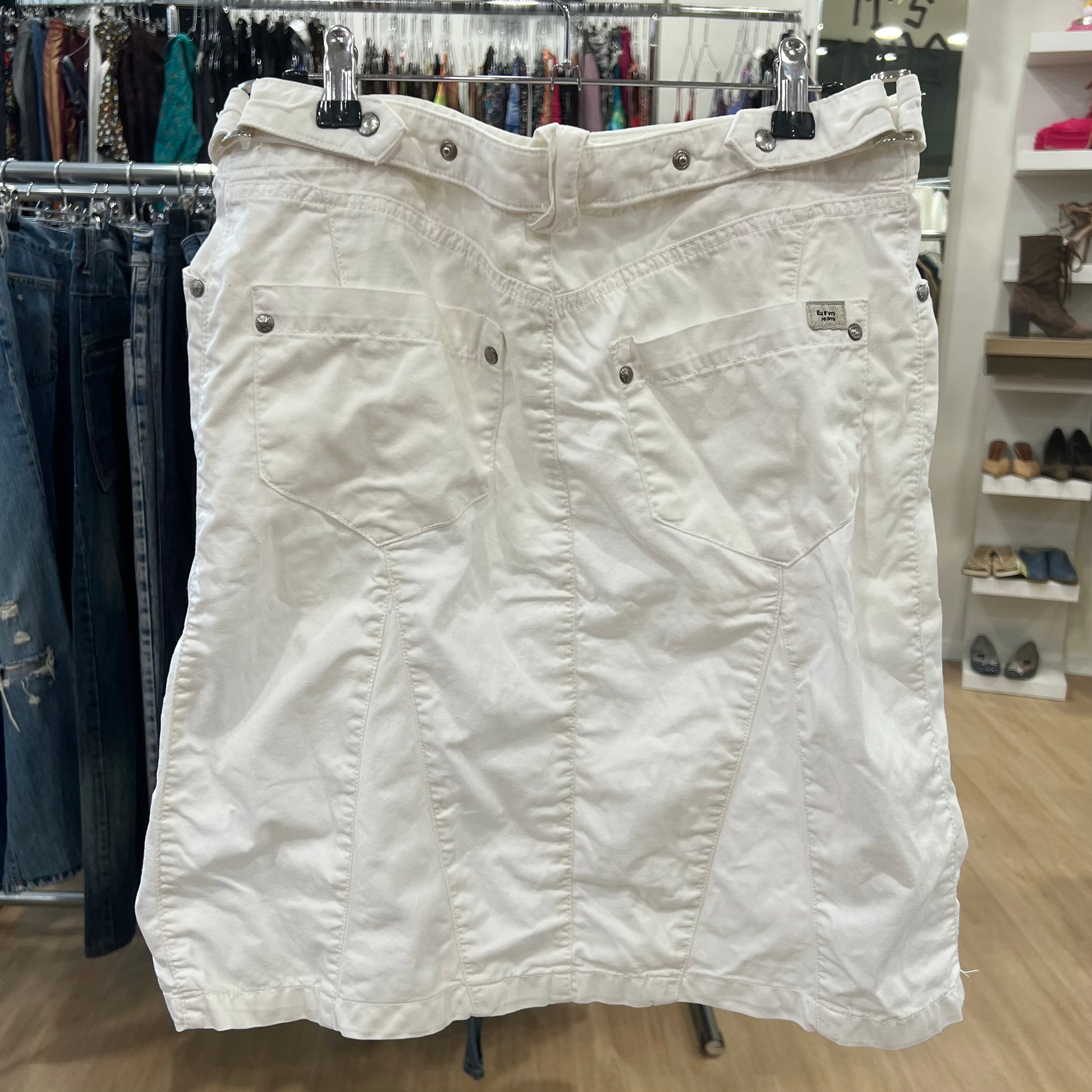 White denim skirt hanging on a rack in a store setting