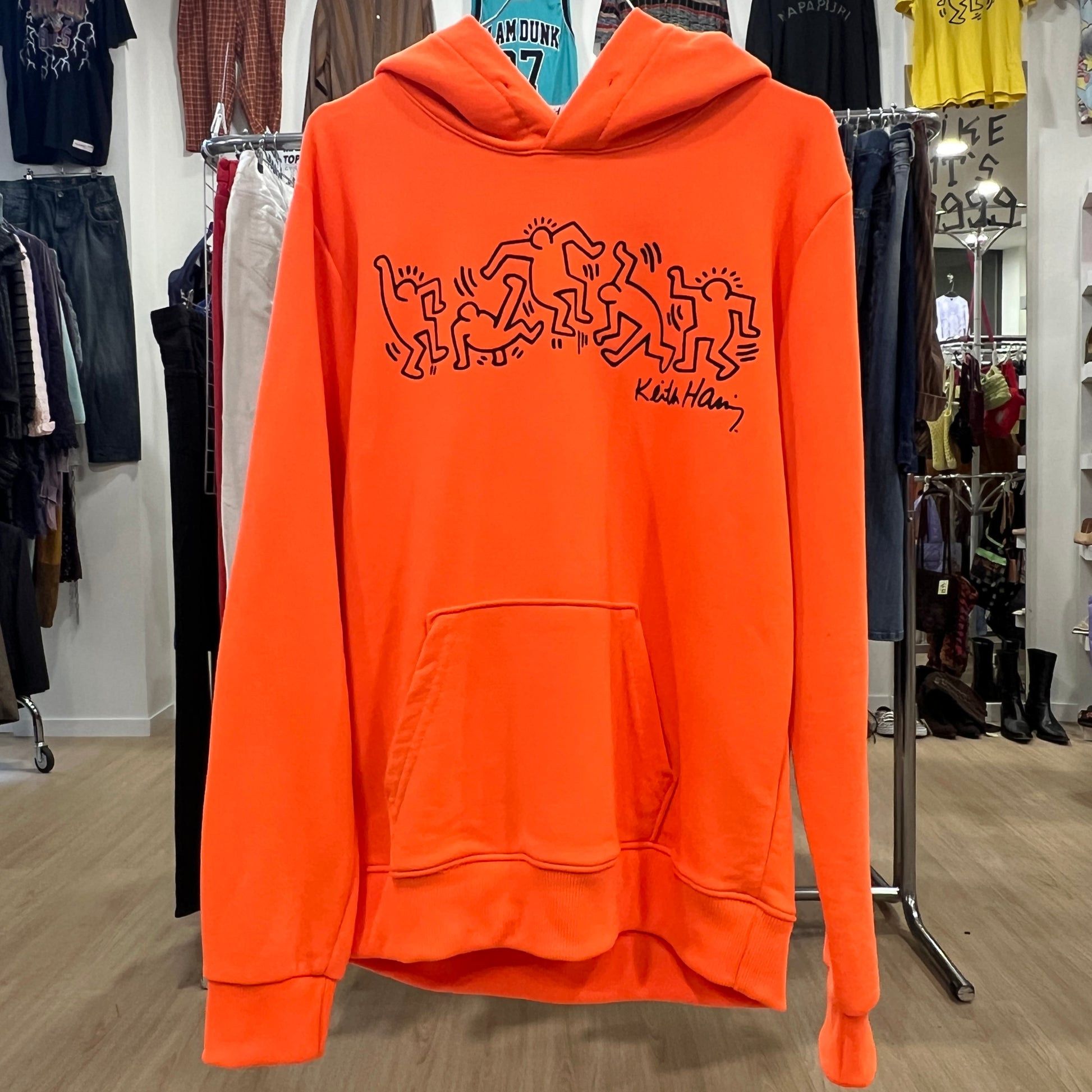 Orange hoodie with black graphics in a store setting