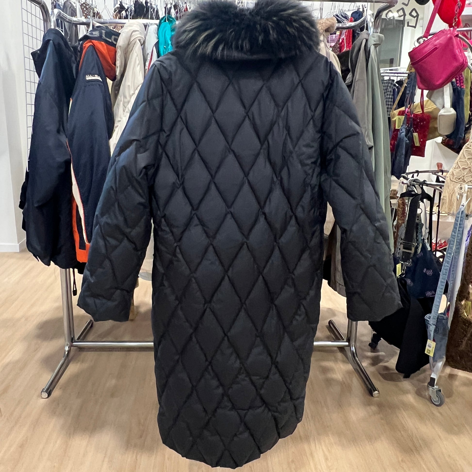 Black quilted coat with fur hood in a store setting