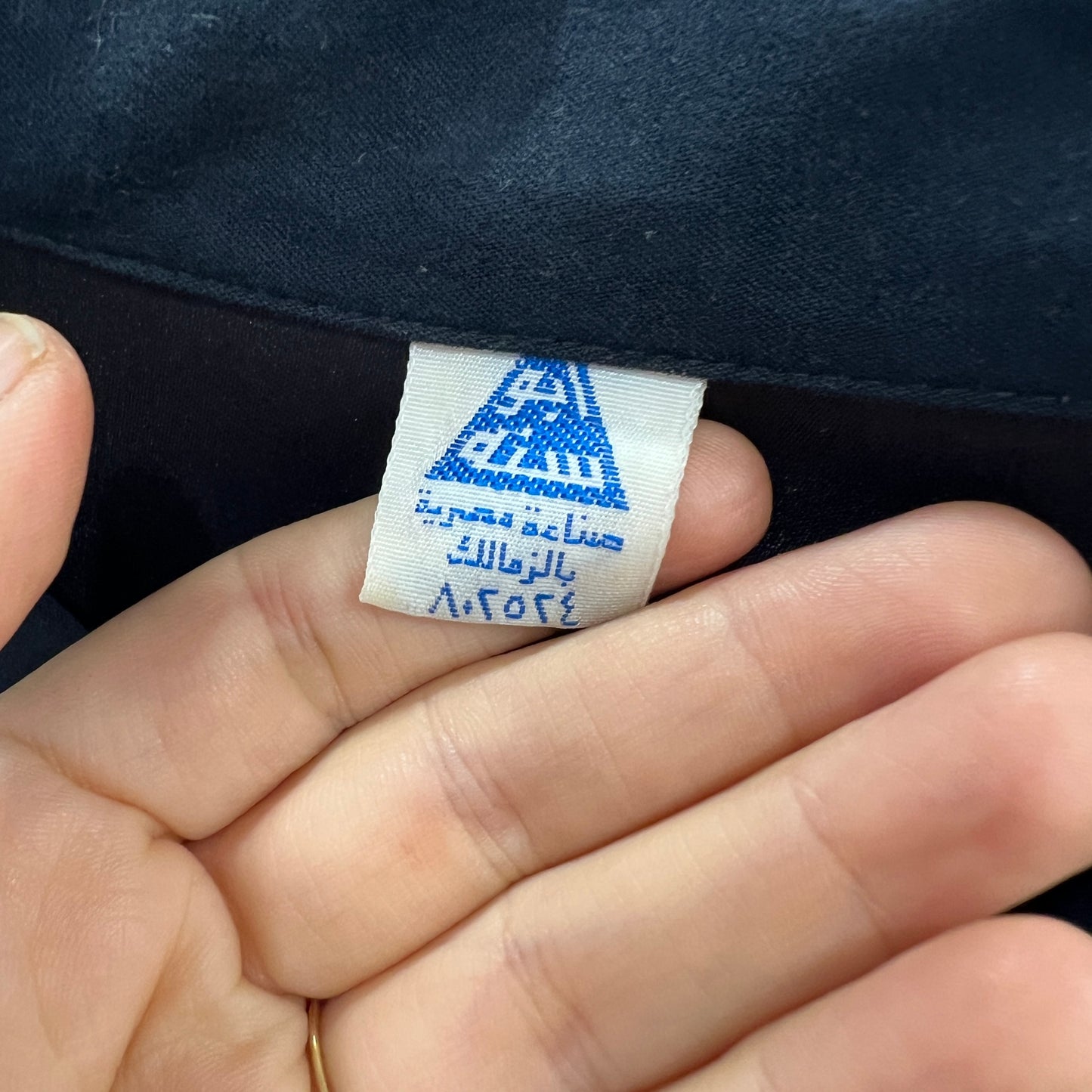 Close-up of a label on a dark fabric with visible text and symbols