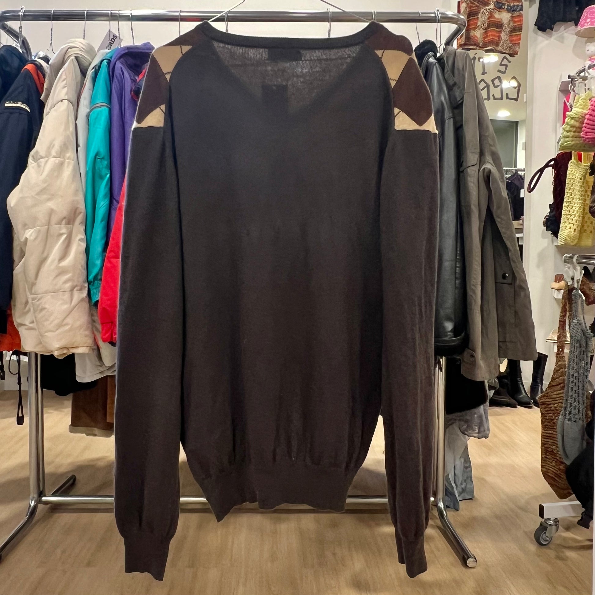 Dark brown sweater on a rack with other clothing items in a store setting