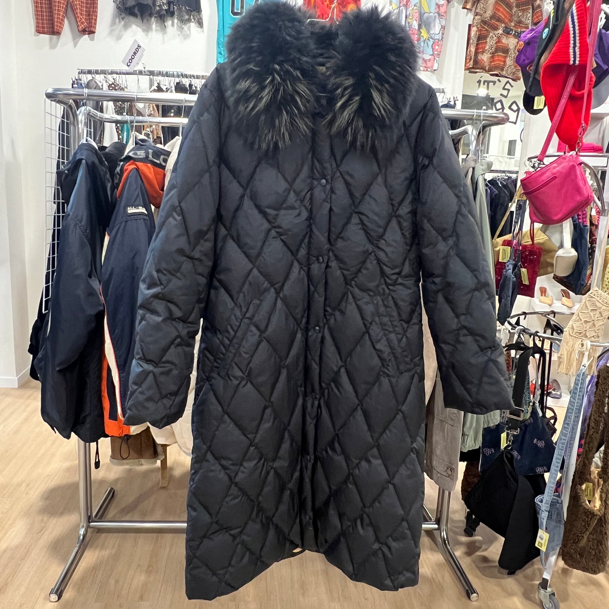 Black quilted coat with fur hood in a store setting