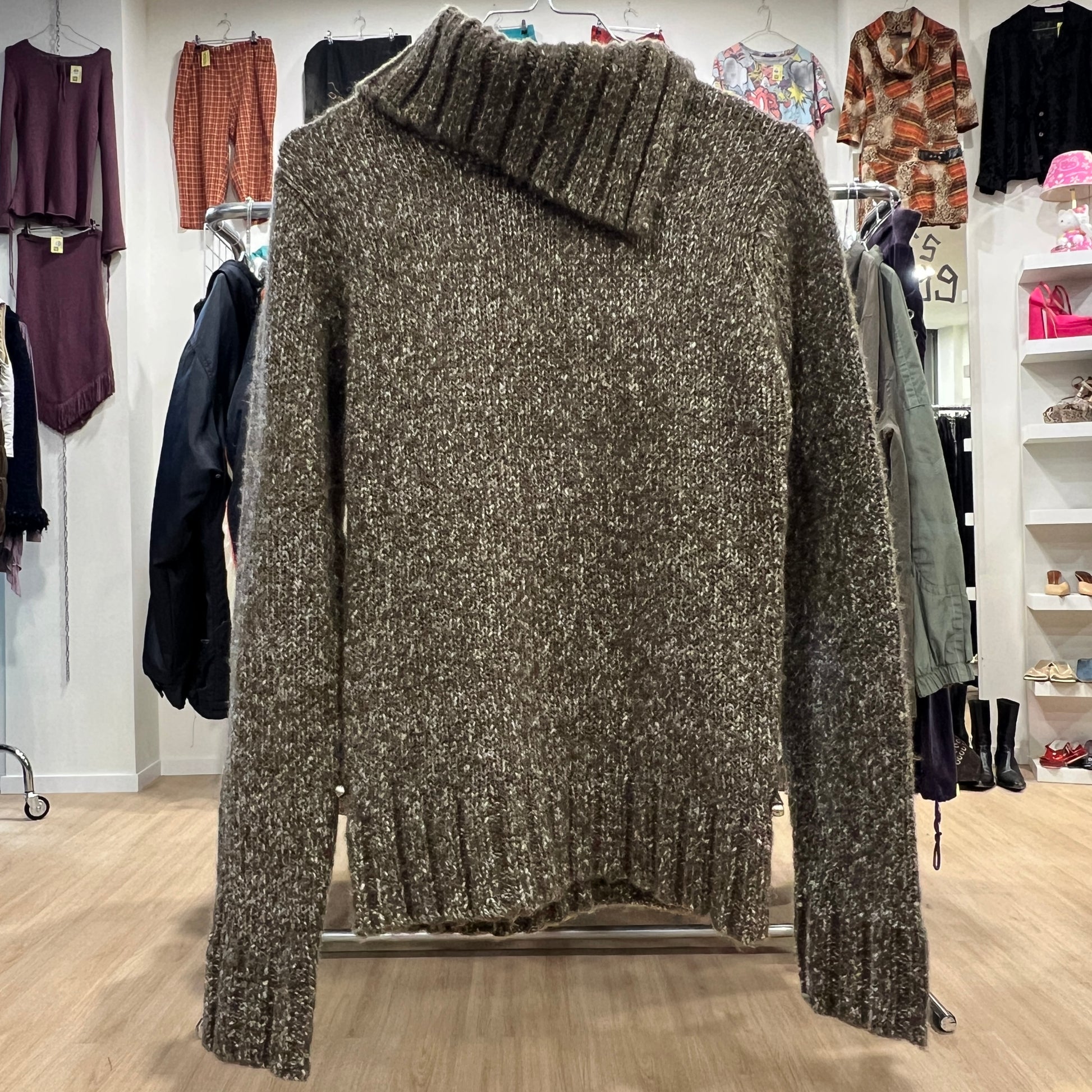 Textured sweater on a rack in a store setting with various clothing items in the background