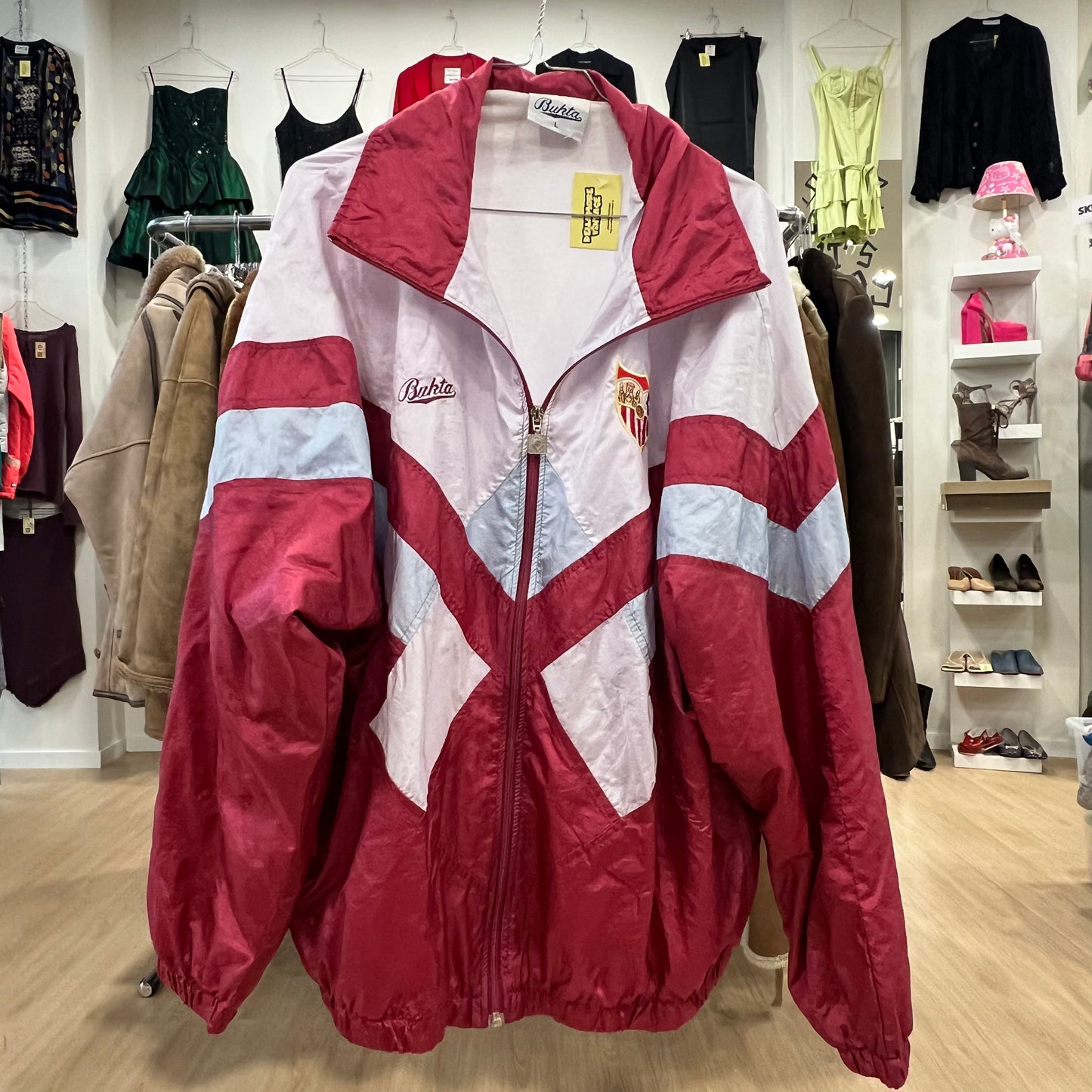 Red and white track jacket with visible brand logo in a clothing store setting