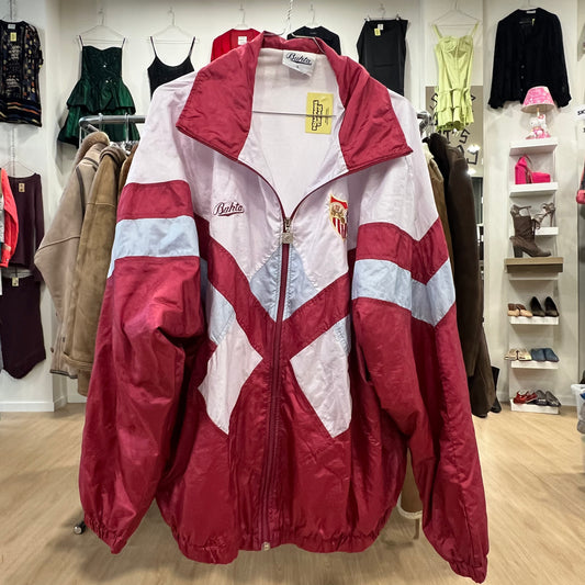 Red and white track jacket with visible brand logo in a clothing store setting
