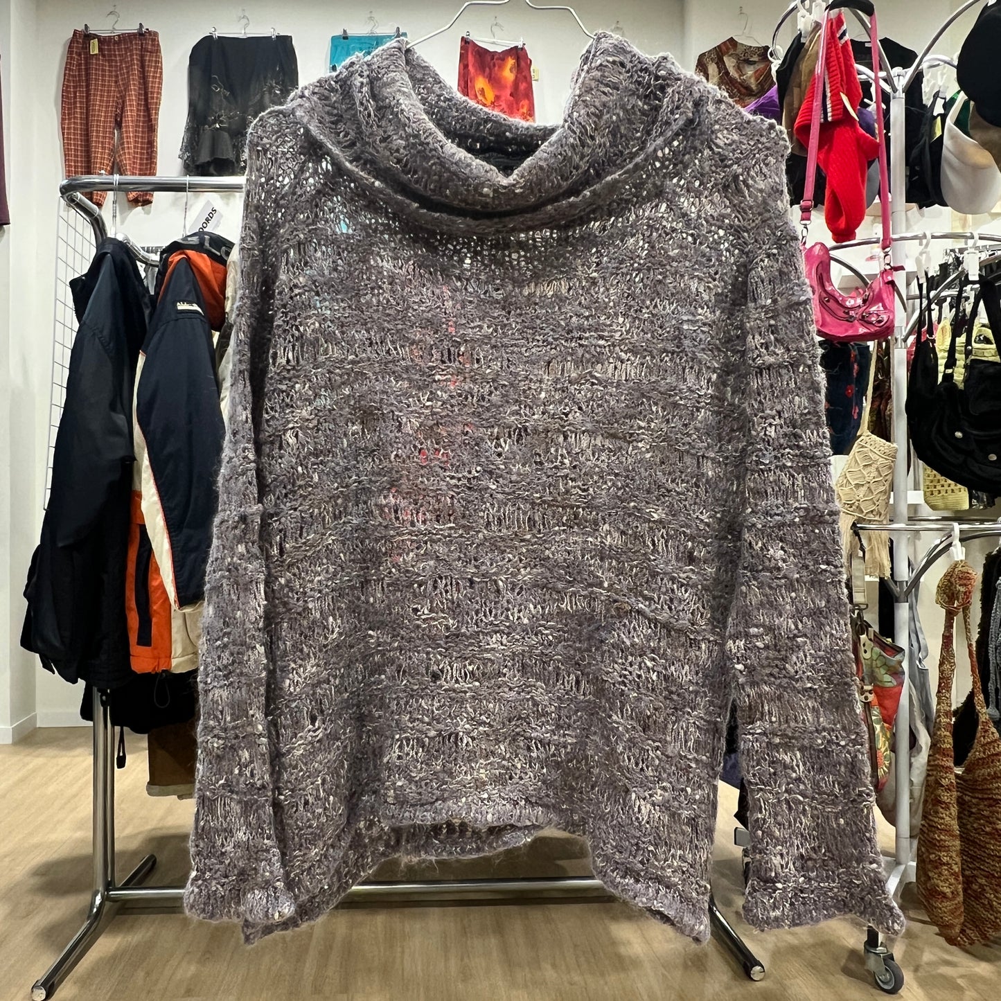Gray textured sweater on a hanger with a clothing store background