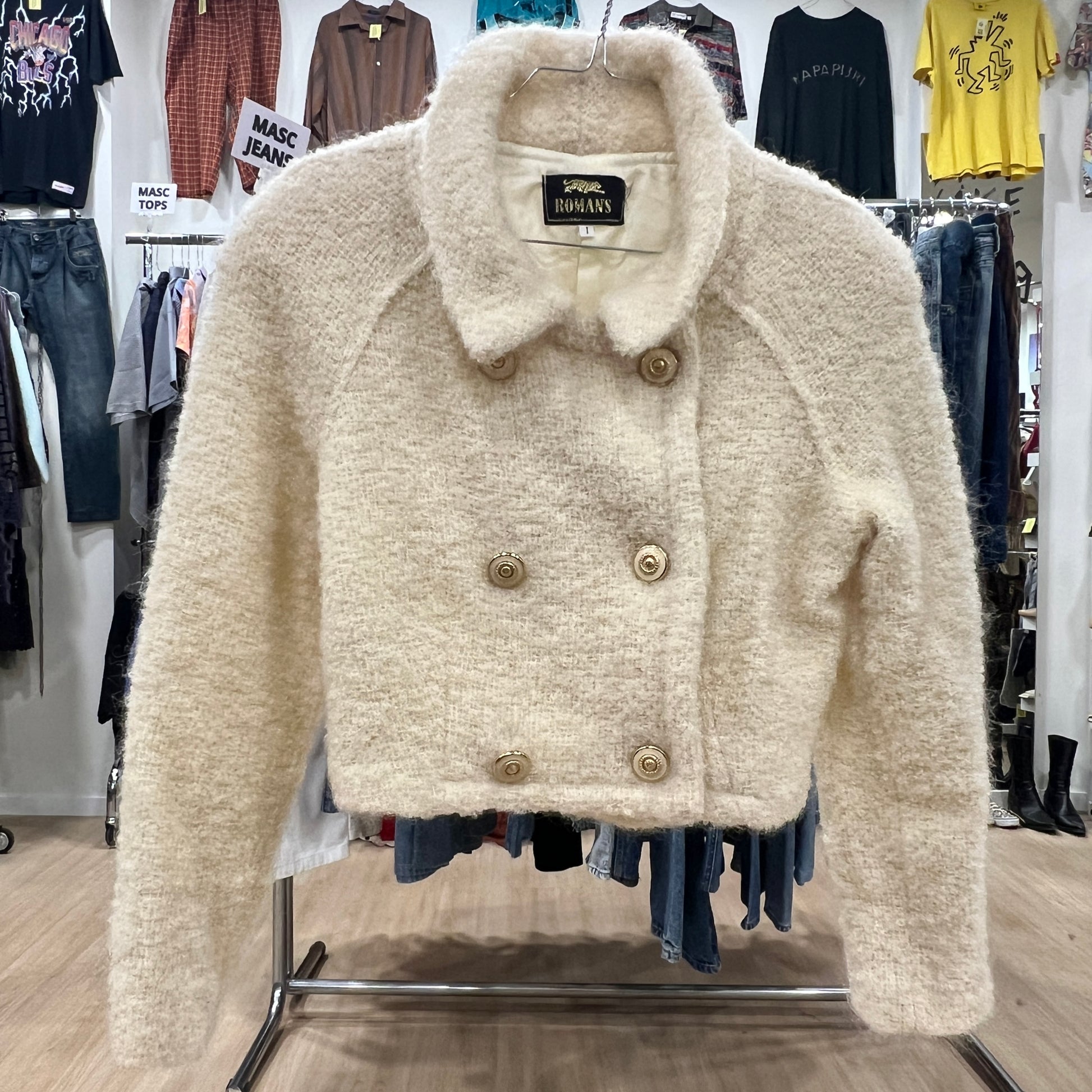 Beige coat with gold buttons on a rack in a clothing store