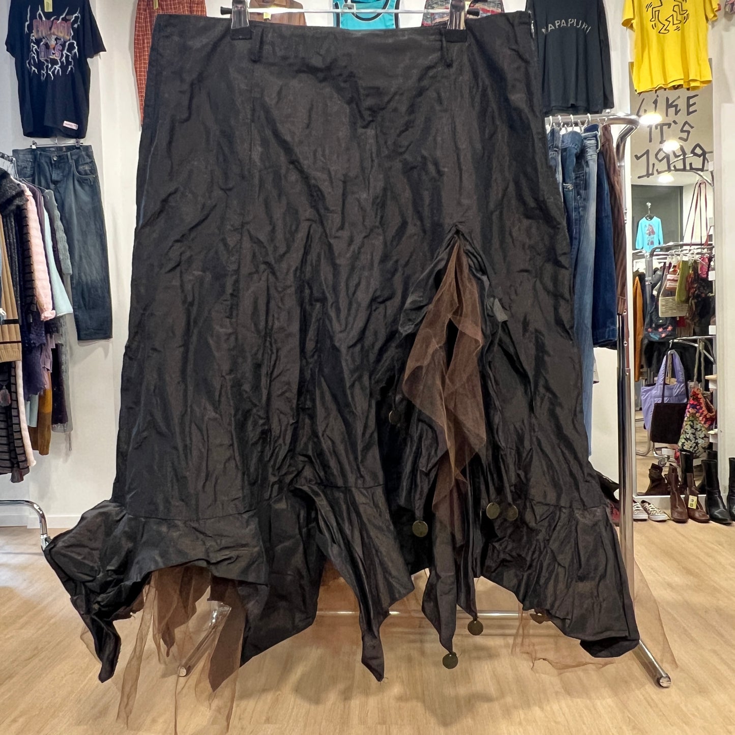 Black textured skirt on a rack in a store setting with various clothing items in the background