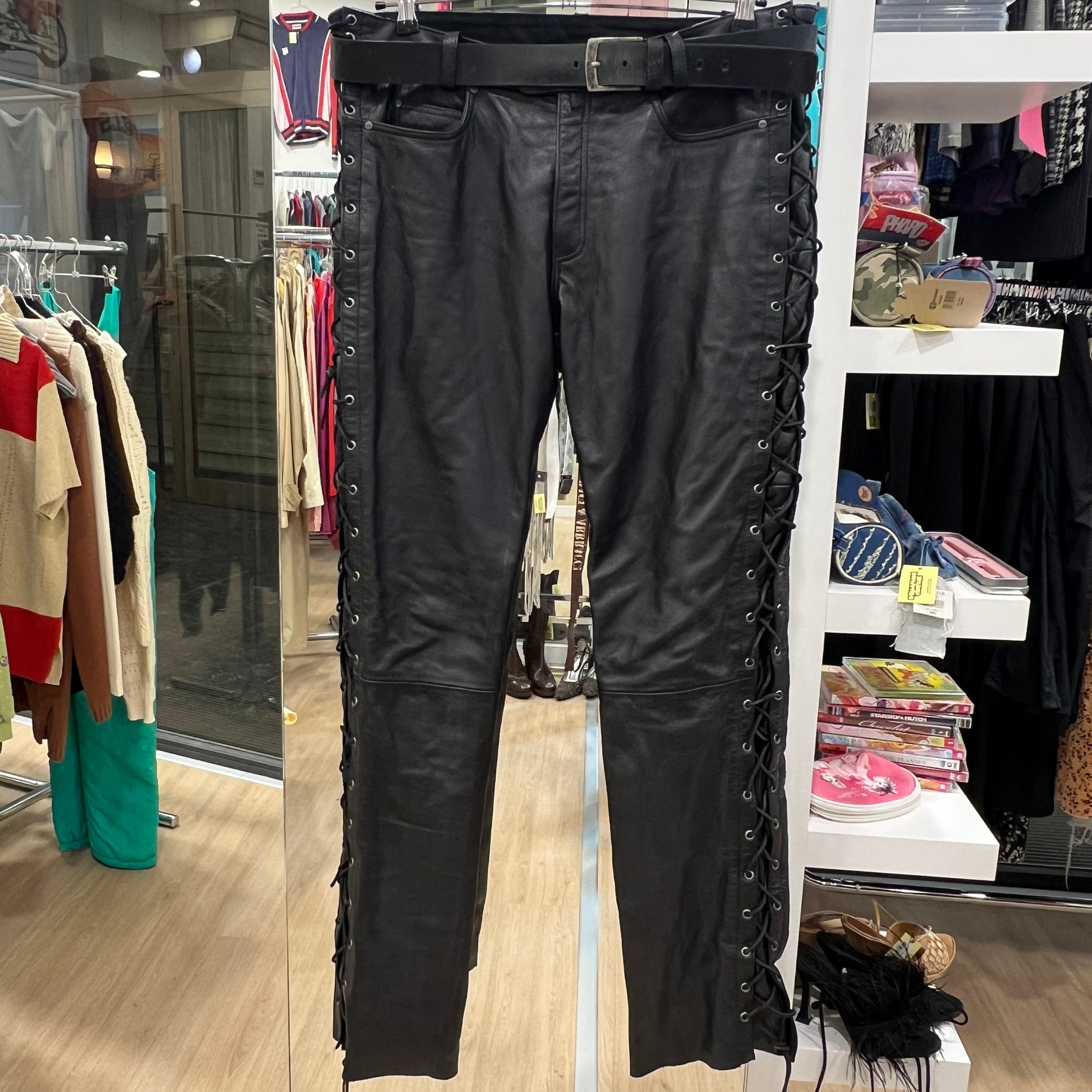 Black leather pants with lace-up sides on a rack in a store setting
