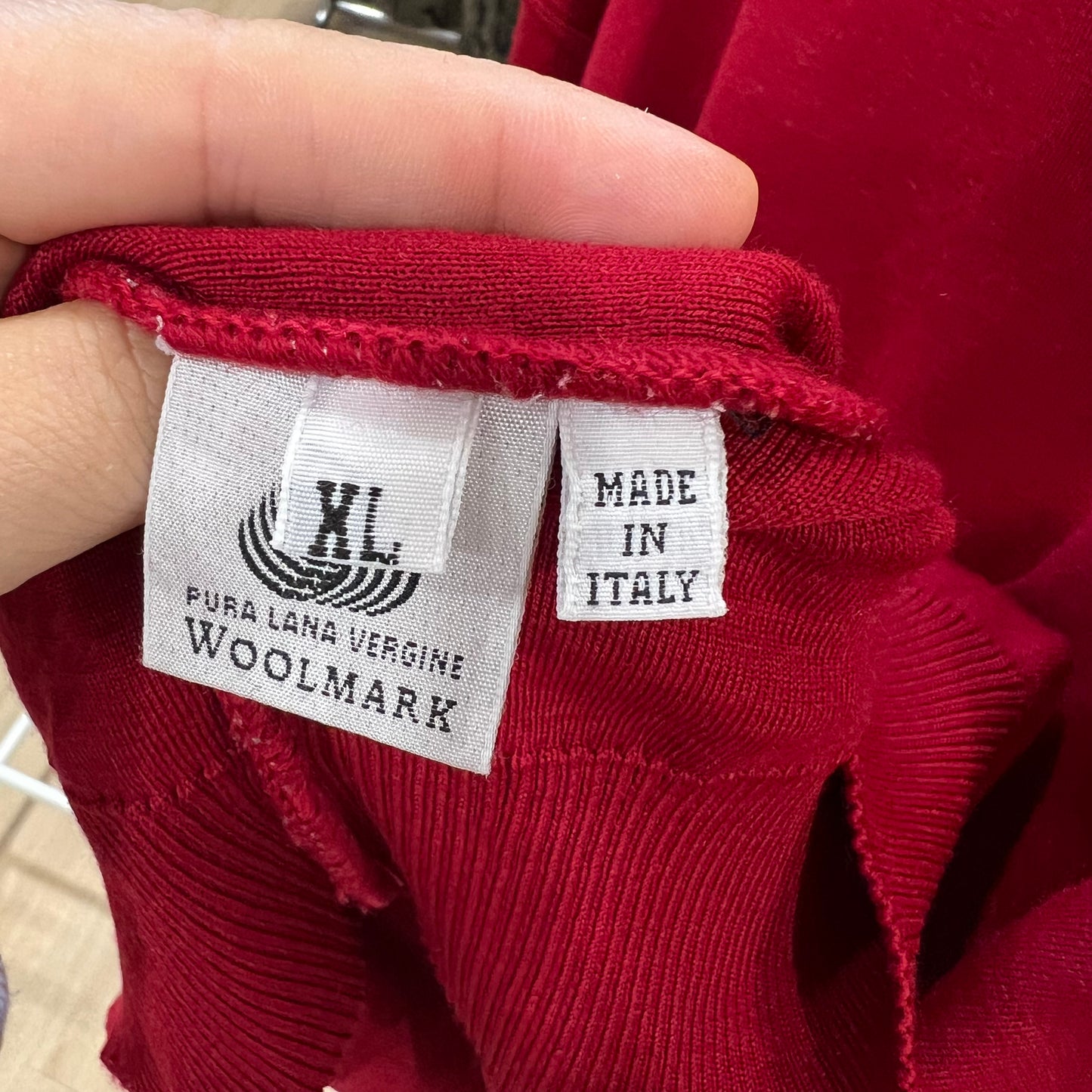 Red garment with a label indicating 'Made in Italy' and 'Woolmark' certification