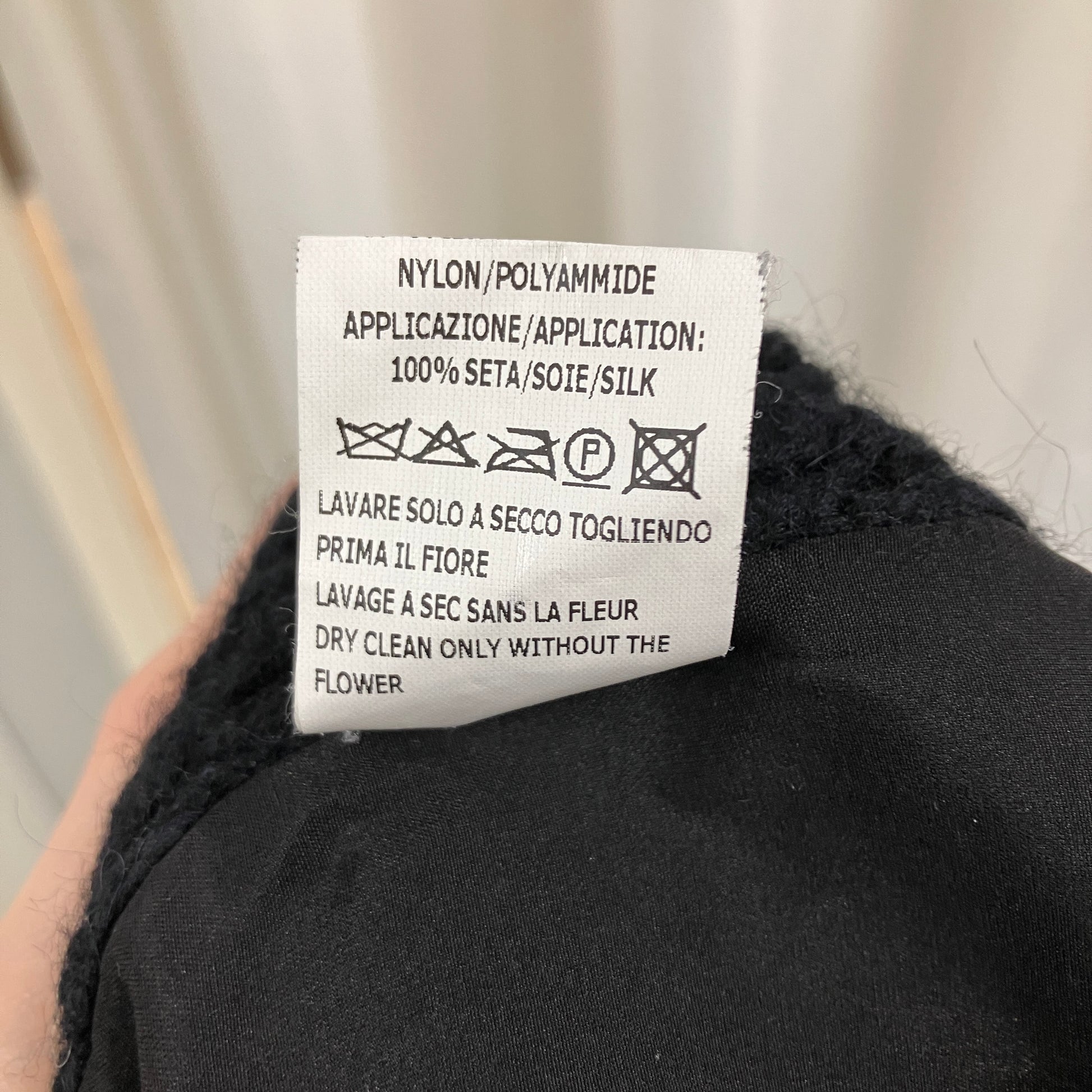 Clothing label on a black garment with text and symbols