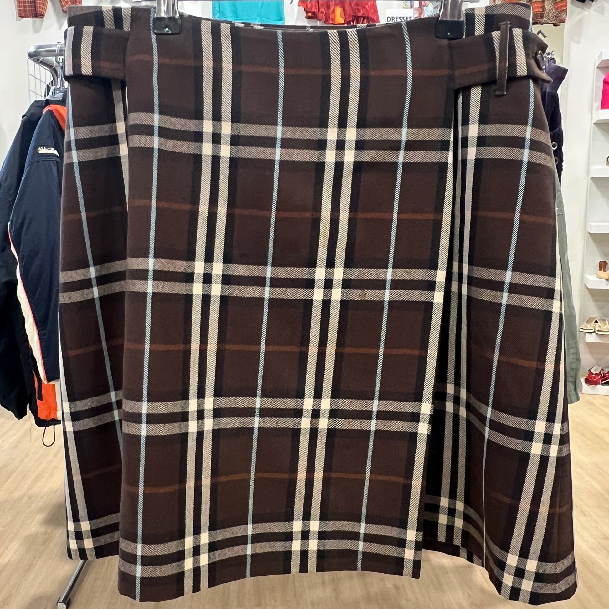Brown plaid skirt on a hanger in a store setting