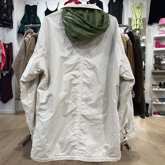 White jacket with green hood on a hanger in a store setting