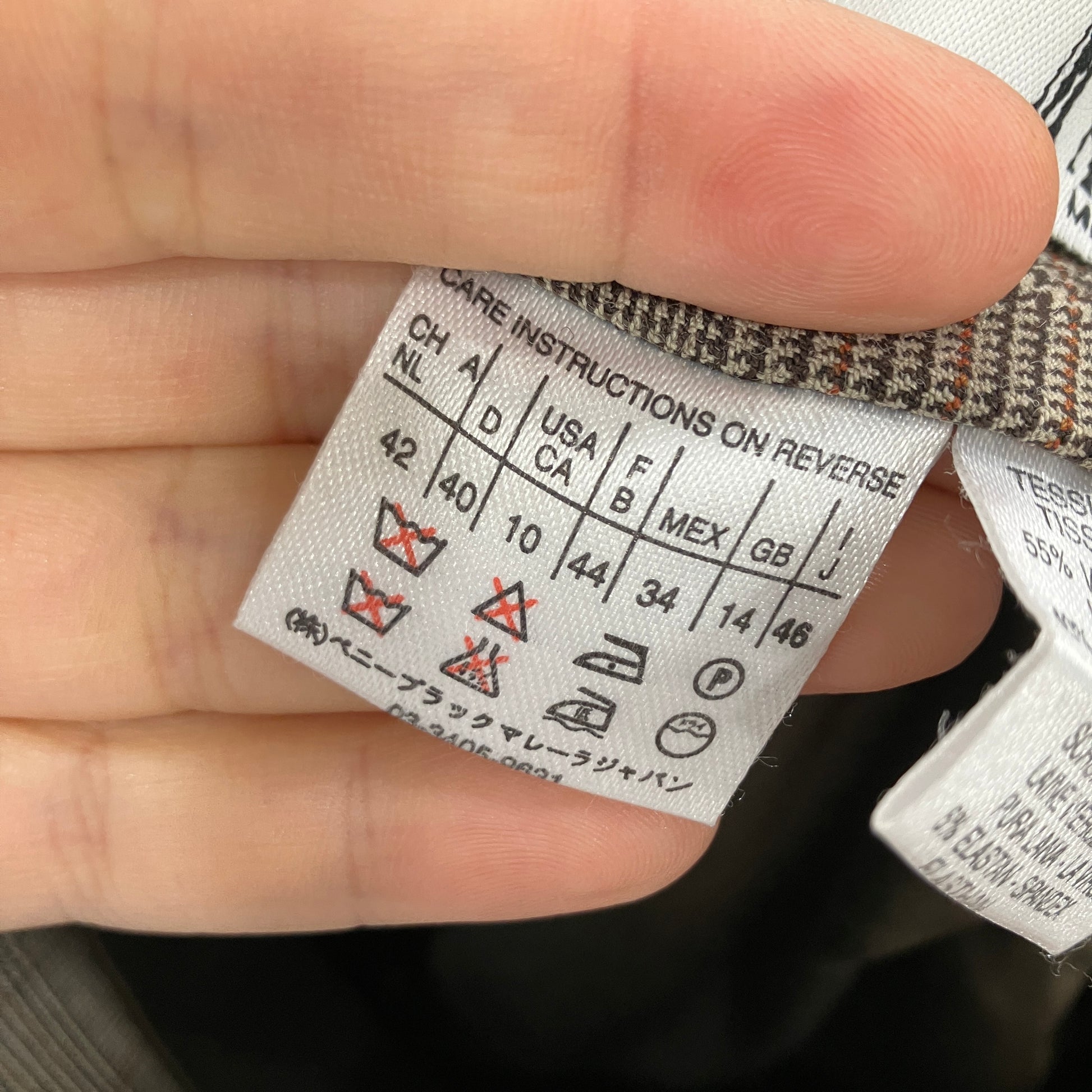 Clothing label with care instructions held by a hand