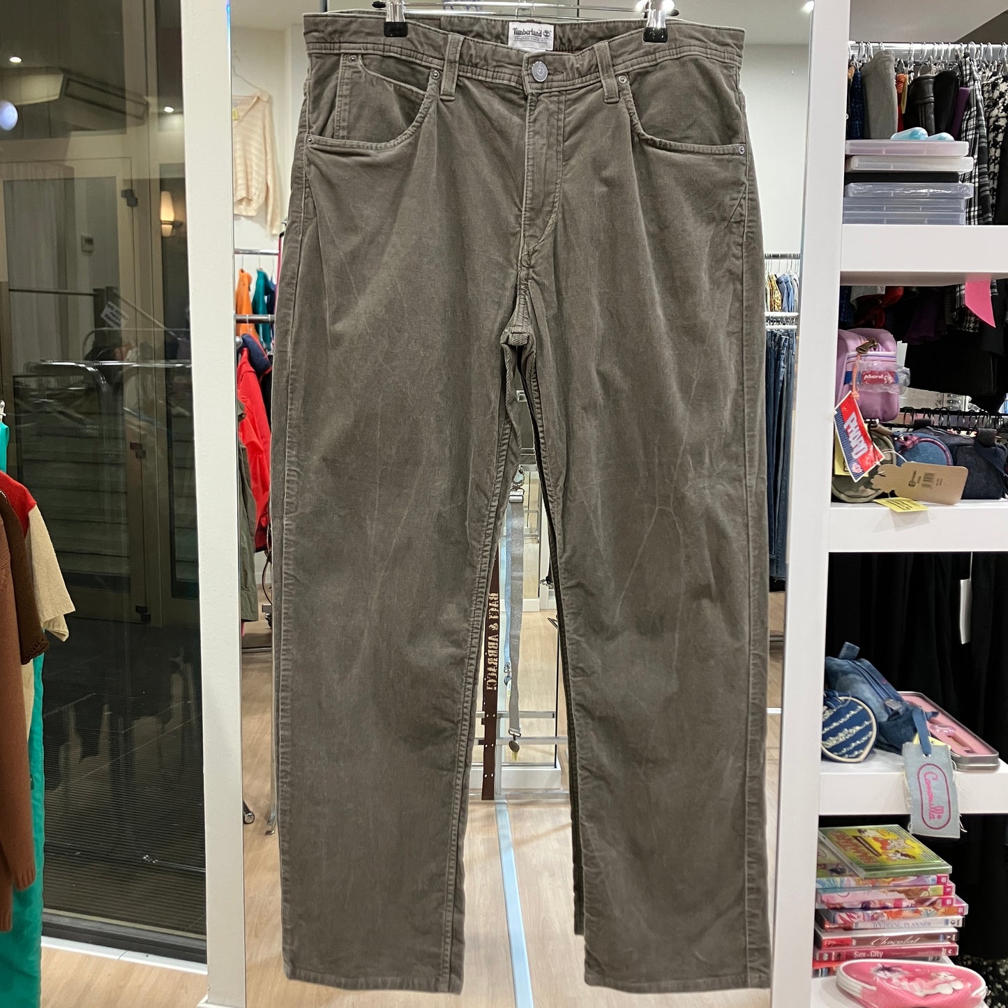 Green pants hanging on a rack in a store setting