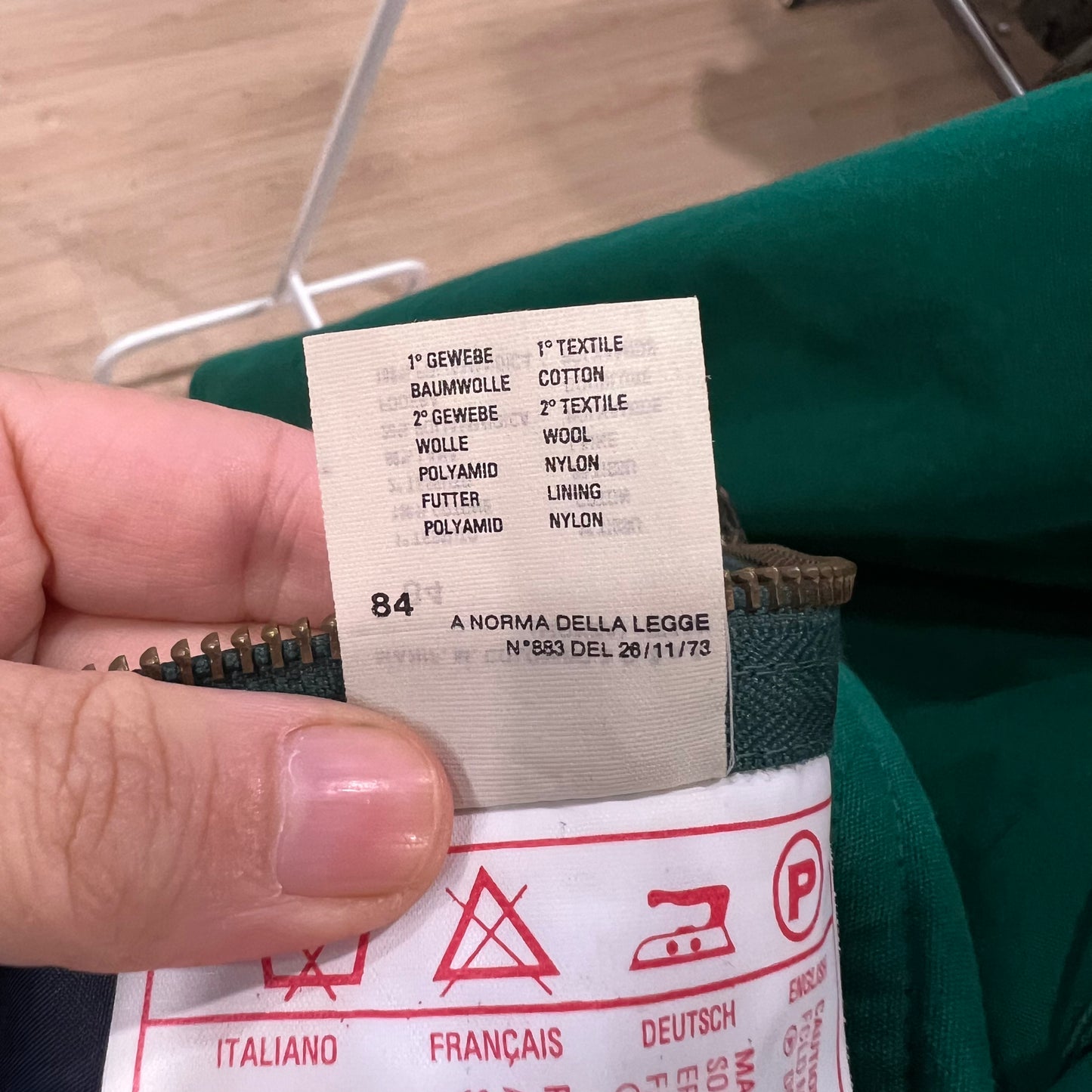 Close-up of a clothing label on a green garment with a blurred background