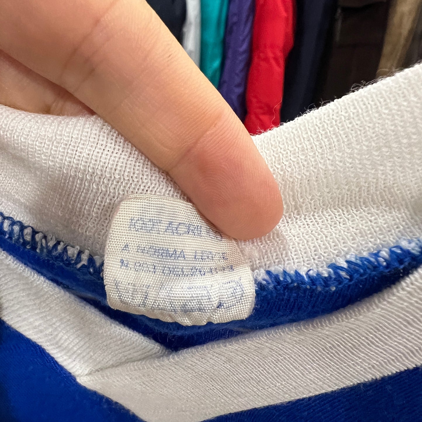 Close-up of a label on a blue and white striped fabric with a hand touching it