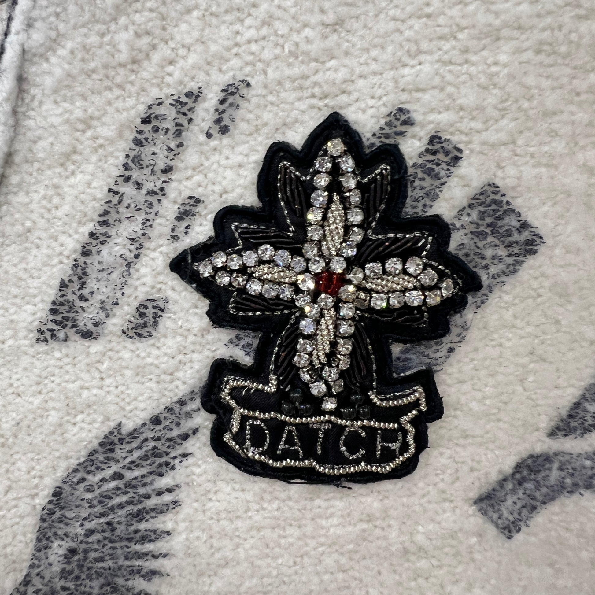 Decorative cross with 'DATCH' text on a textured surface