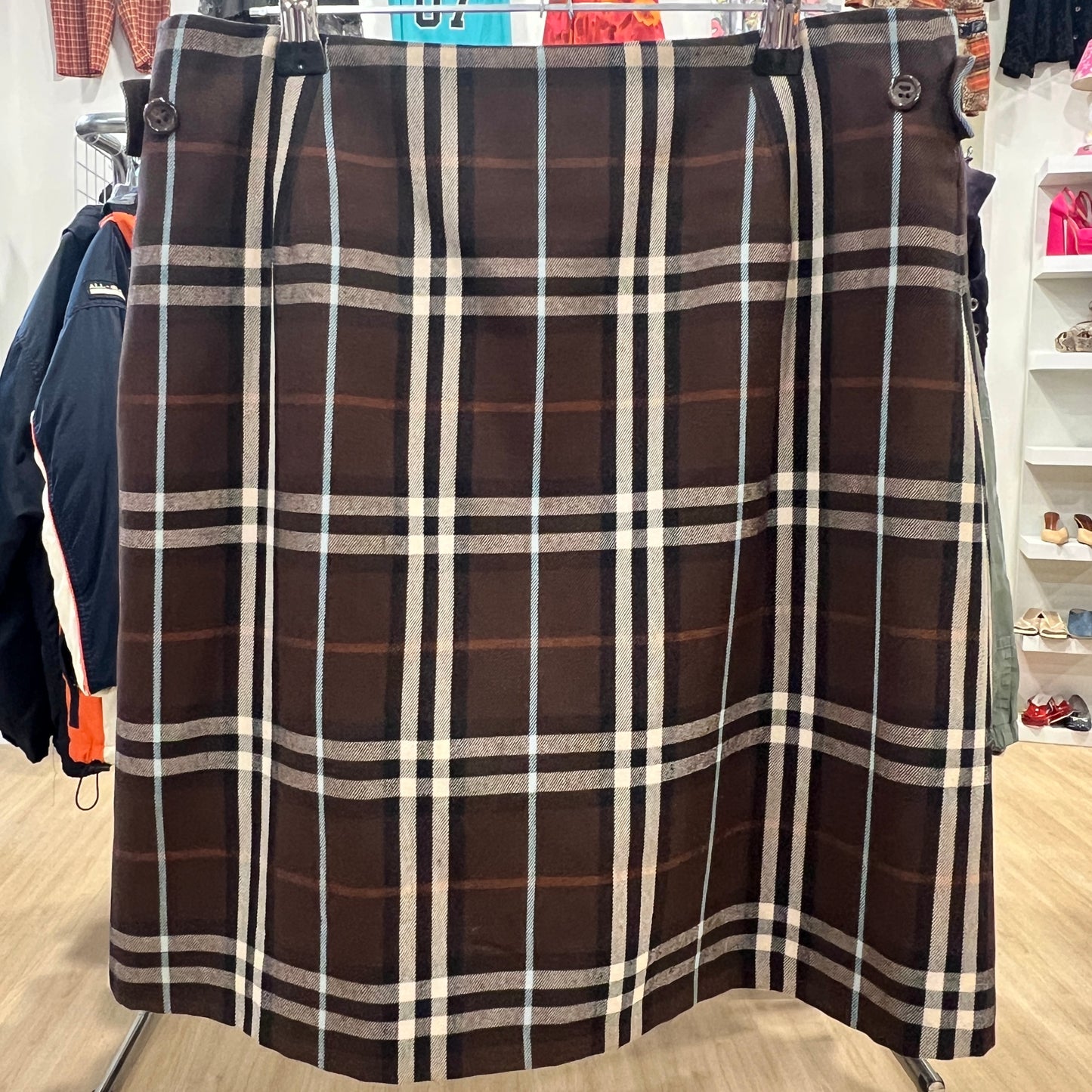 Plaid skirt hanging in a store with clothing in the background