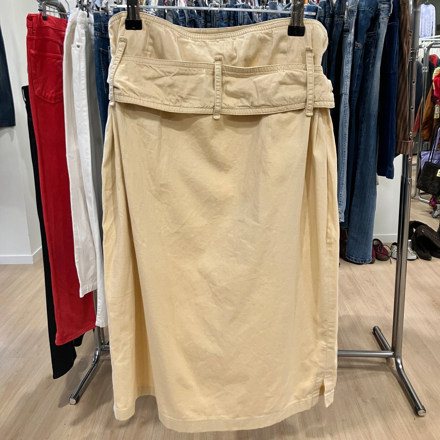 Beige skirt hanging on a rack with clothing in the background
