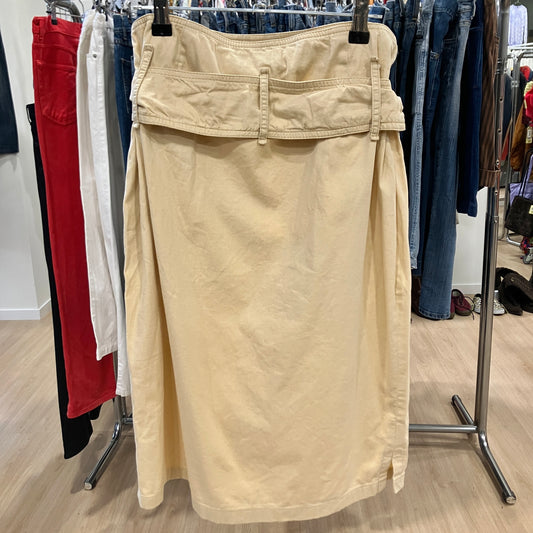 Beige skirt hanging on a rack with clothing in the background