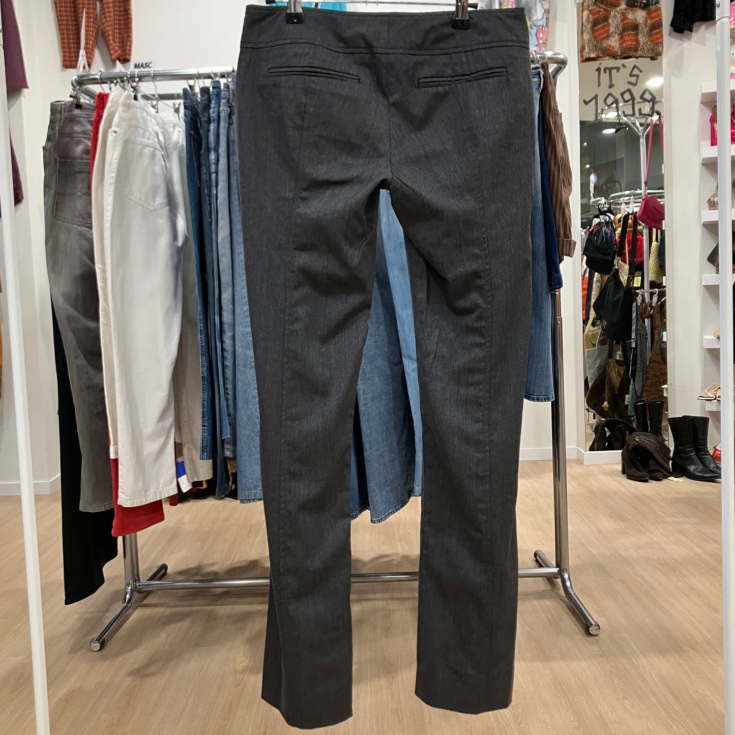 Black pants displayed on a rack in a store setting with various clothing items in the background