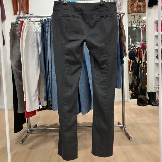 Black pants displayed on a rack in a store setting with various clothing items in the background
