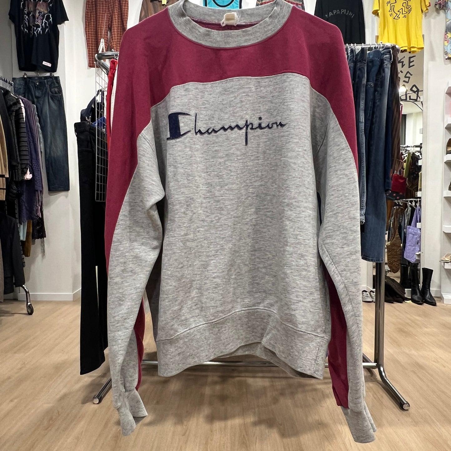 Gray and red Champion sweatshirt on a rack in a store setting