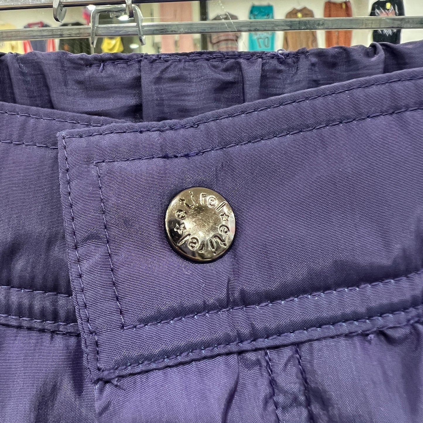 Close-up of a purple jacket with a brand logo on a hanger