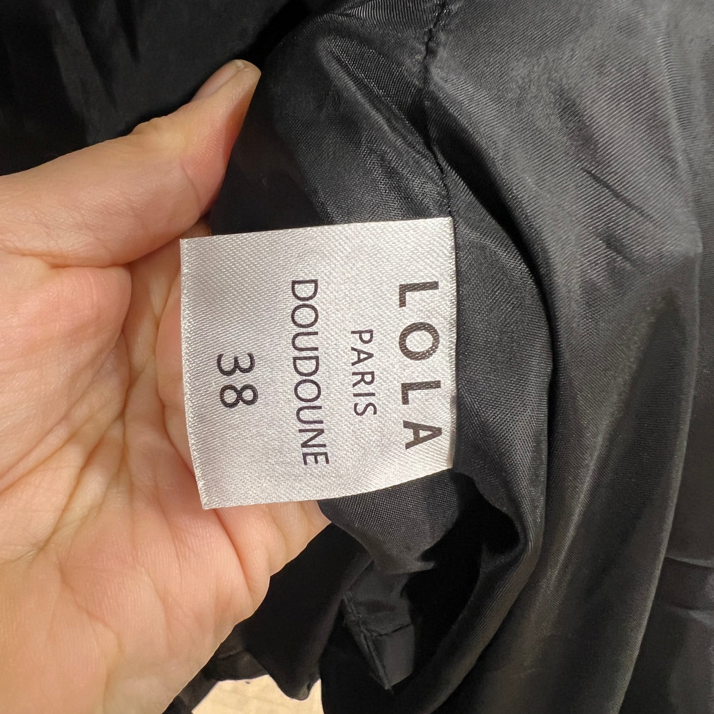 Clothing label on a black jacket with 'LOLA PARIS' branding