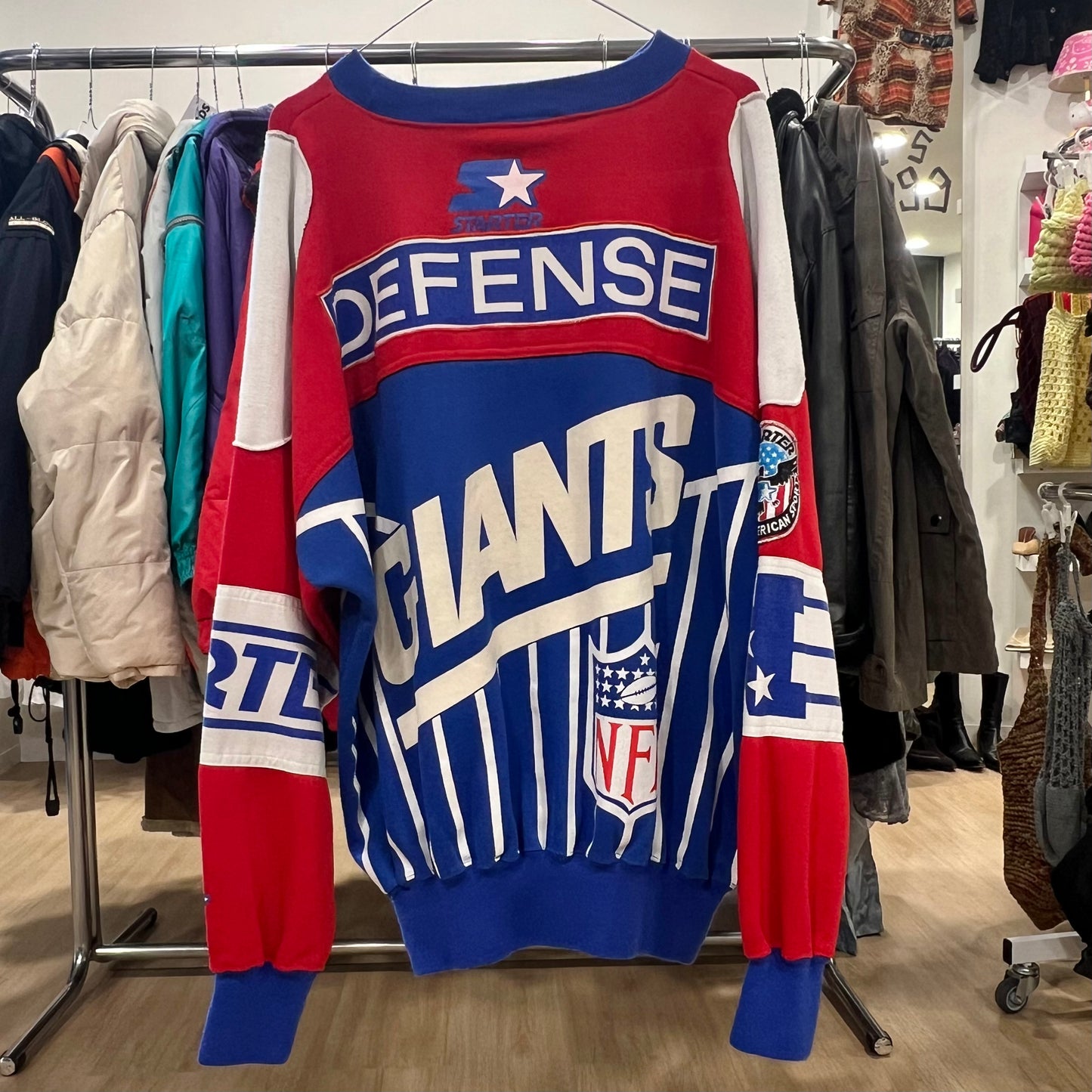 Red and blue sports jersey with 'Defense Giants' text on a rack in a store