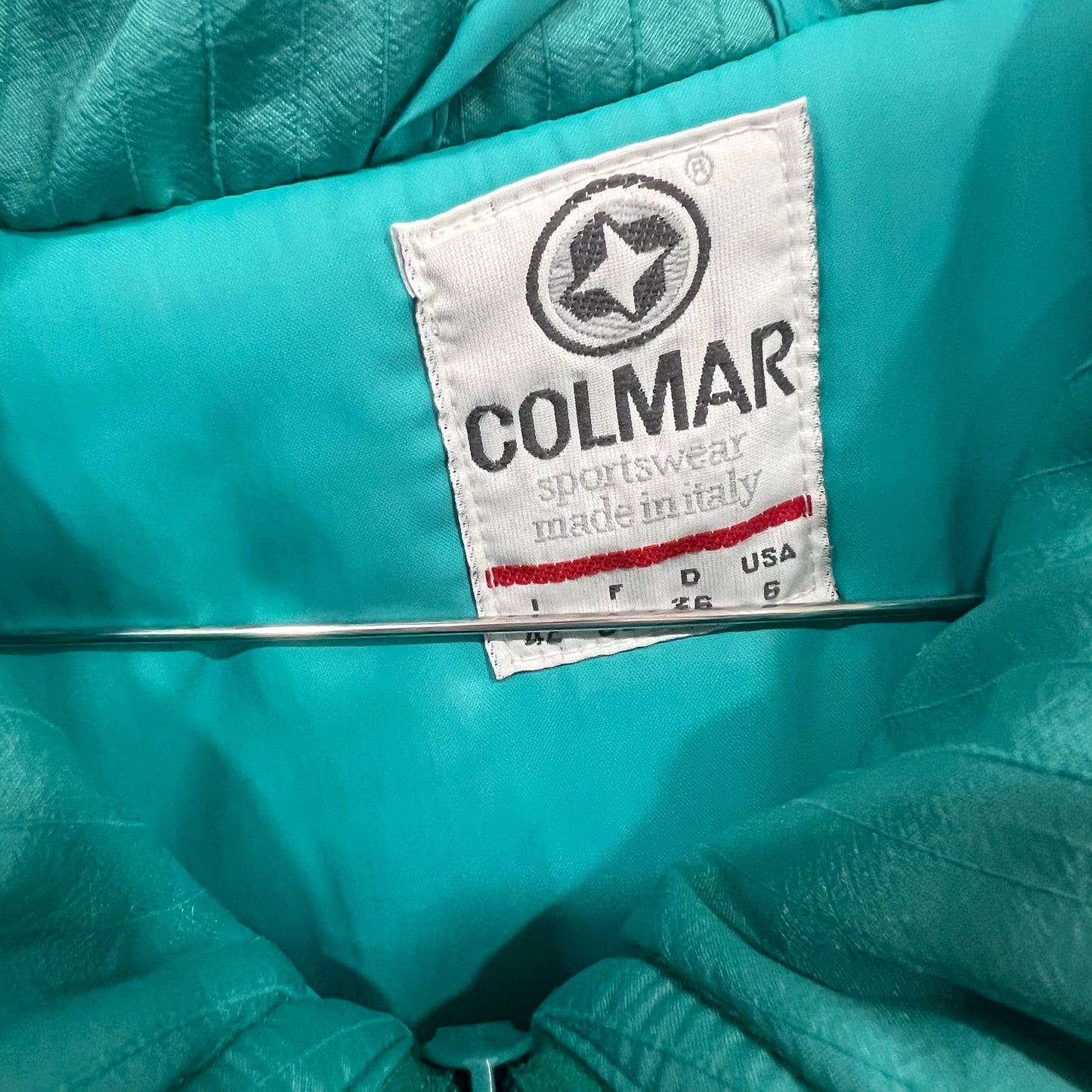 Close-up of a Colmar sportswear label on a teal jacket