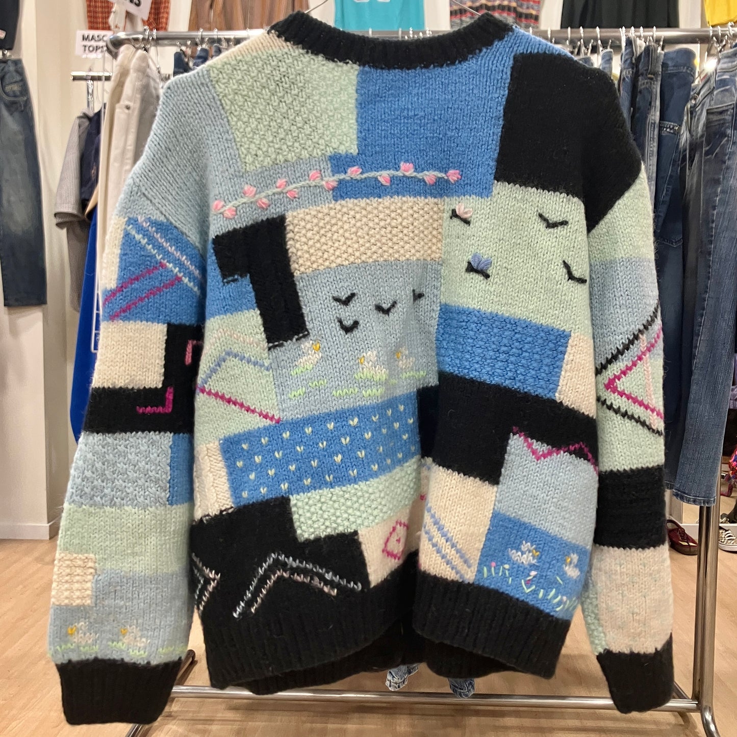Colorful patchwork sweater on a rack in a store setting