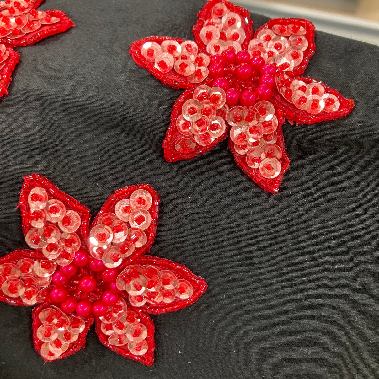 Red floral sequin patches on a black fabric background