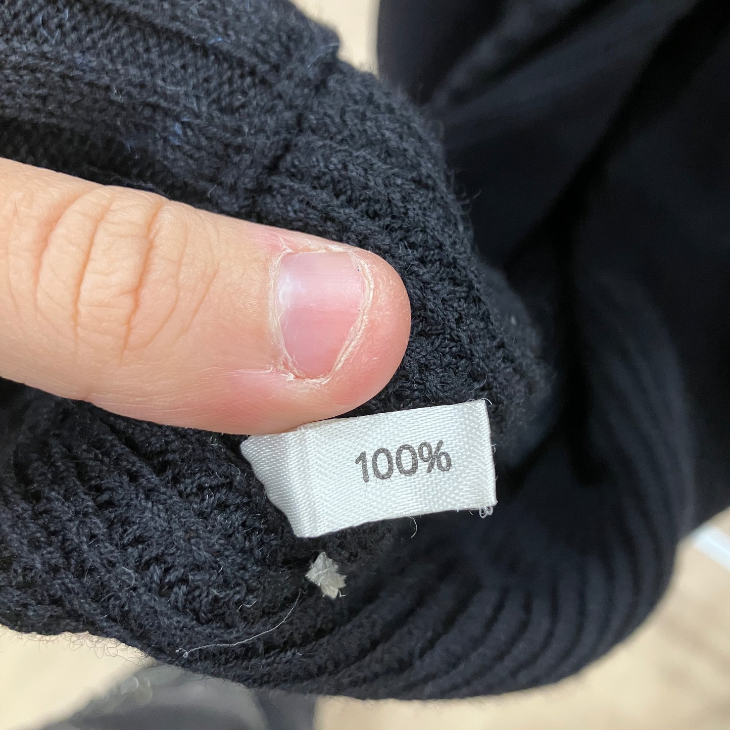 Close-up of a black knitted fabric with a '100%' label